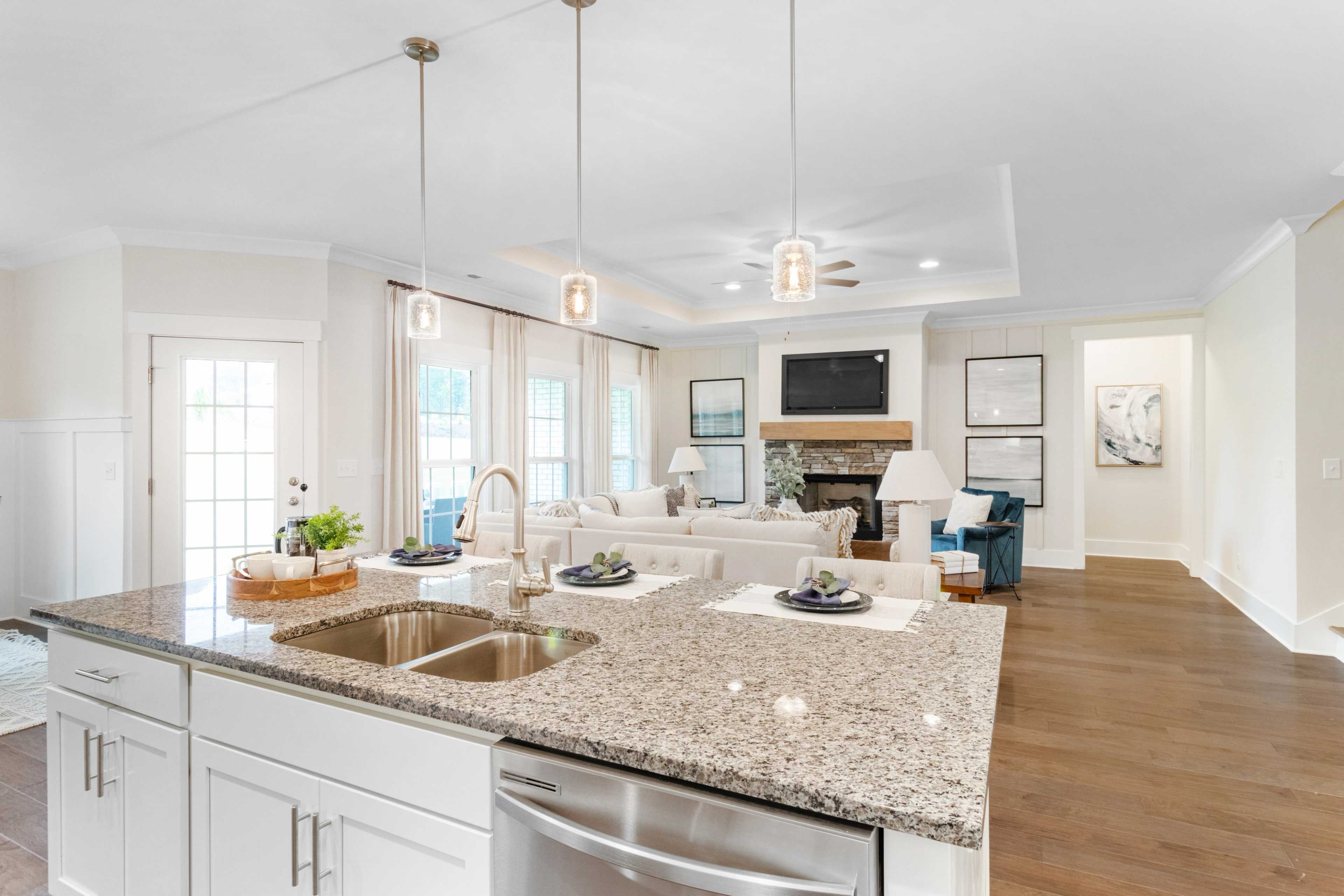Spacious open-concept kitchen living area in Noble Ridge Cullman AL with granite island white cabinets fireplace and hardwood floors