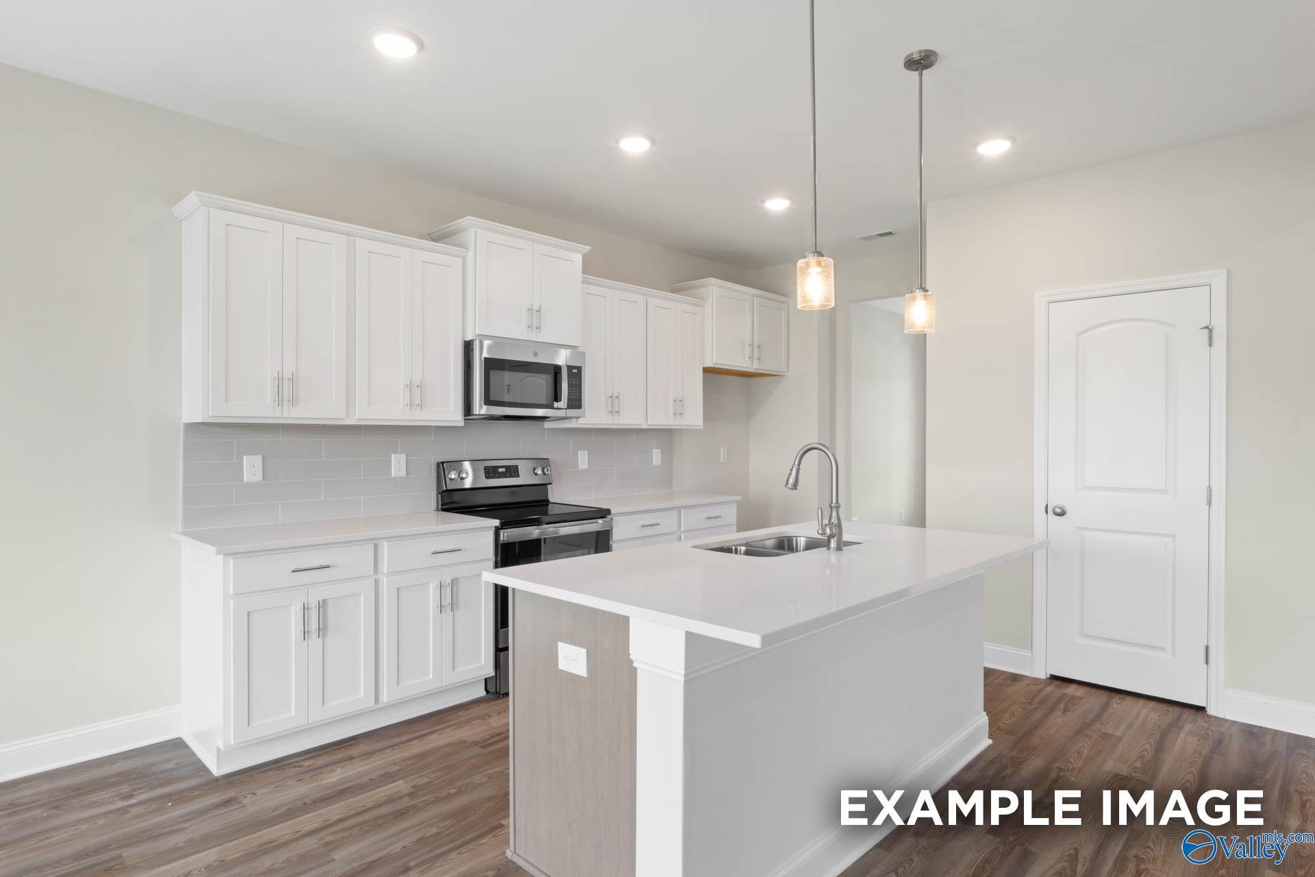 Modern kitchen with white cabinets, quartz countertops, and center island in The Shelby B floor plan, Huntsville, Alabama.