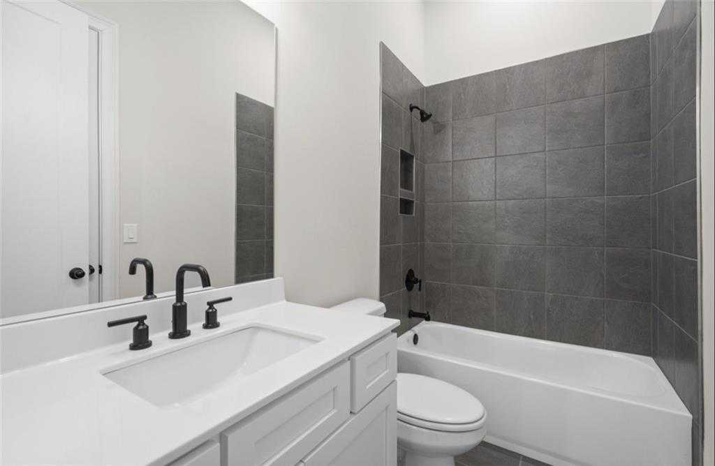 Modern bathroom featuring white vanity, black fixtures, gray tile walk-in shower, and soaking tub in Davidson Homes The Seaside A, Woodstock, GA