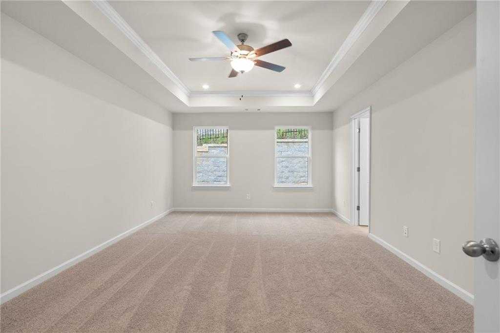 Spacious empty bedroom with tray ceiling, ceiling fan, dual windows, and carpet in Davidson Homes The Marion B, Kennesaw, GA