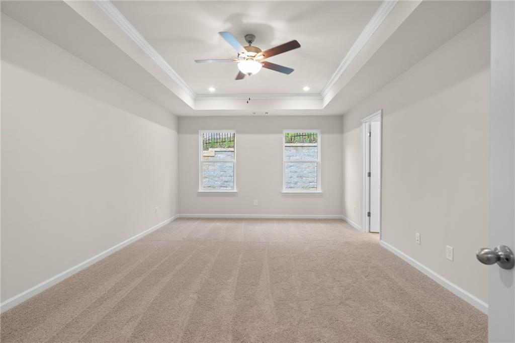 Spacious empty bedroom with tray ceiling, ceiling fan, dual windows, and carpet in Davidson Homes The Marion B, Kennesaw, GA