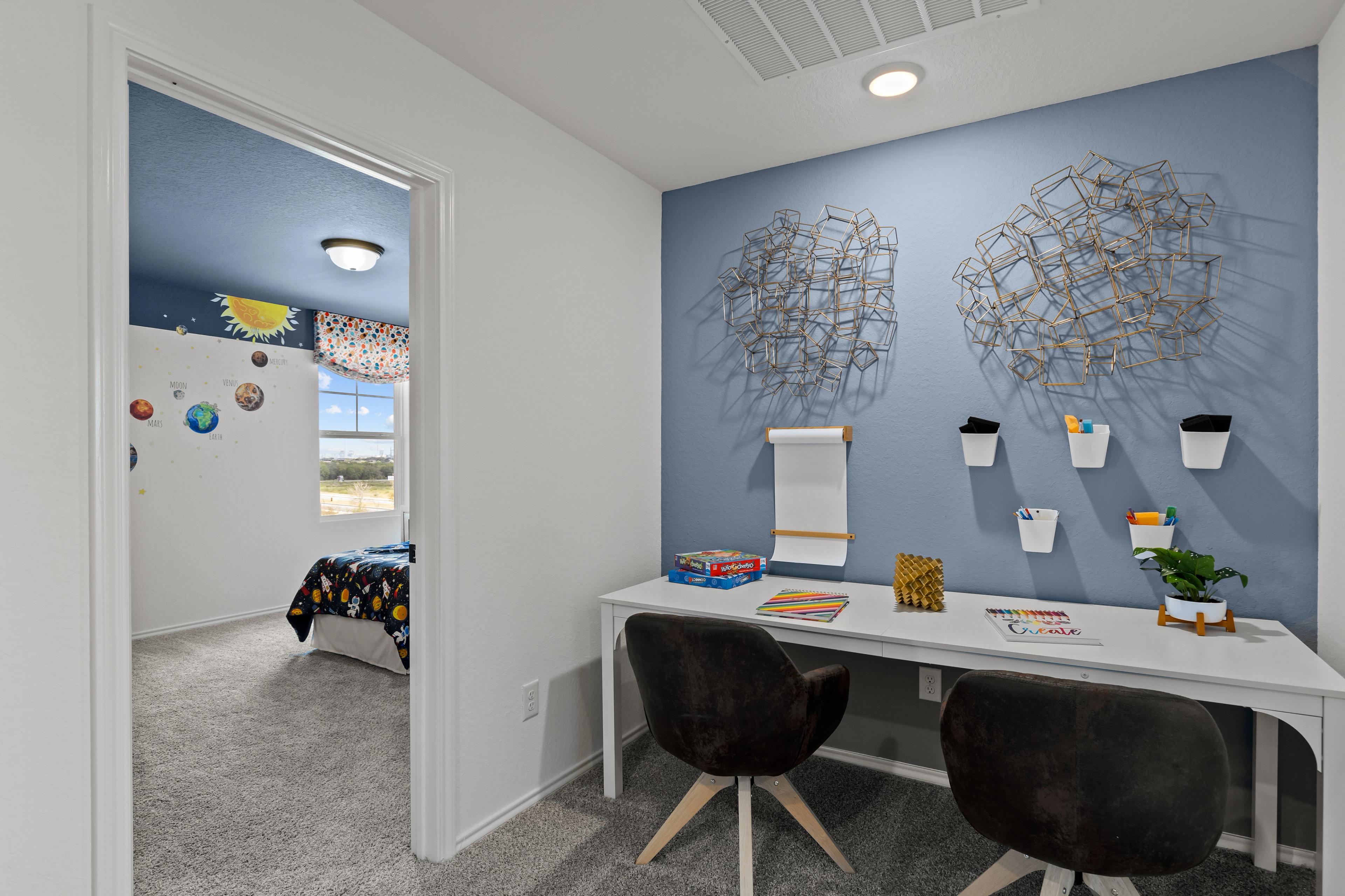 Cozy kids' bedroom in The Douglas F with blue walls, black swivel chairs at white desk, abstract metal art, and open door to colorful bed