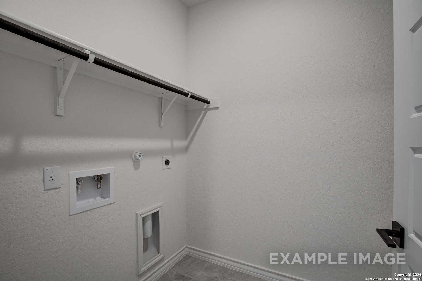 Modern laundry room with built-in shelves, hanging rod, washer-dryer hookups in Davidson Homes The Garner C, Castroville, Texas