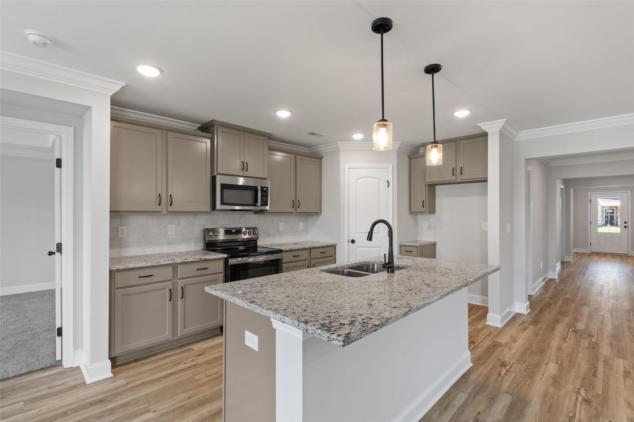 Modern kitchen with granite island, taupe cabinetry, and pendant lighting in The Holly C floor plan, Anna, Texas.