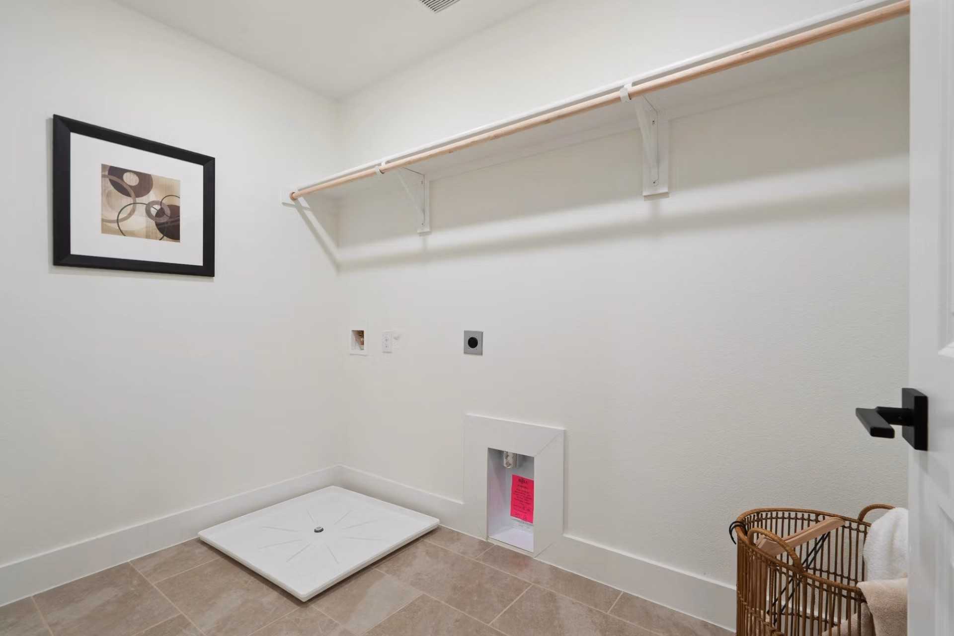 Spacious laundry room with wood shelving, pet shower station, and abstract wall art in Davidson Homes The Wake D, Wylie, Texas