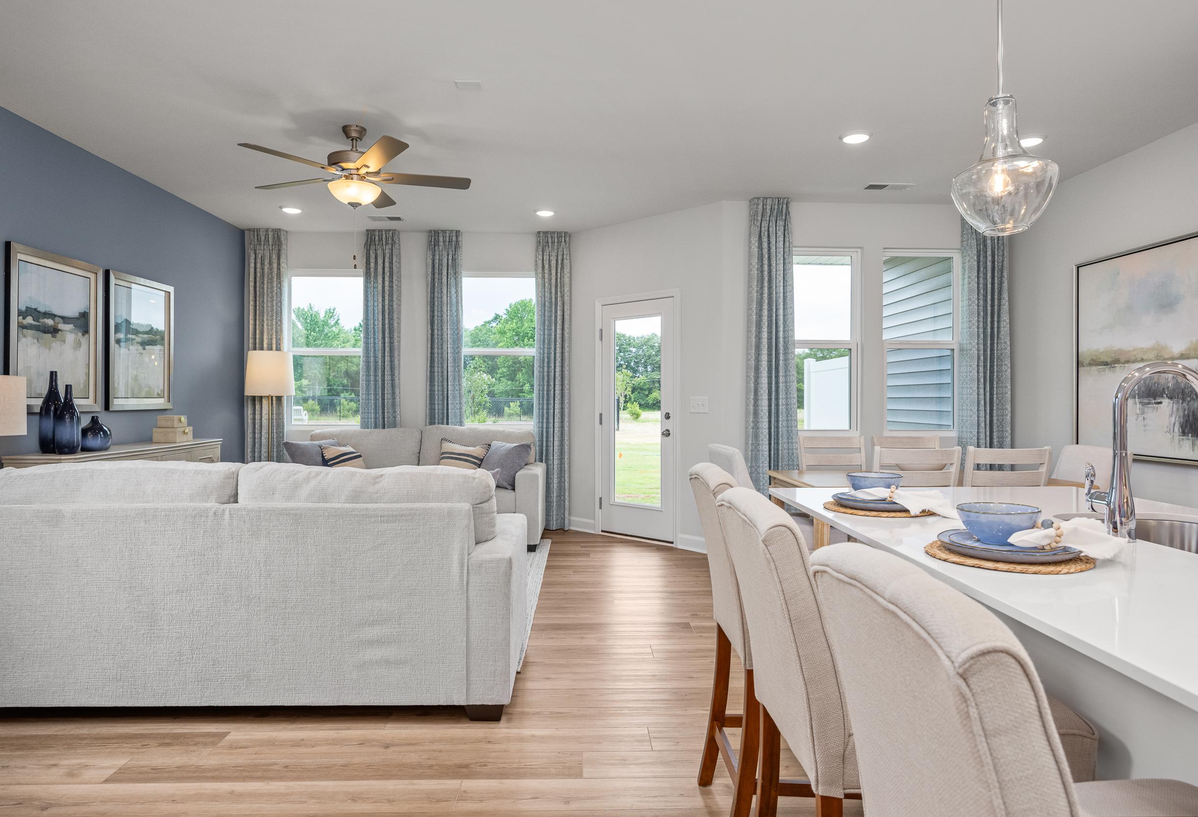 Open-concept living and dining area in The Graham featuring modern kitchen island, stylish blue accents, and natural light.