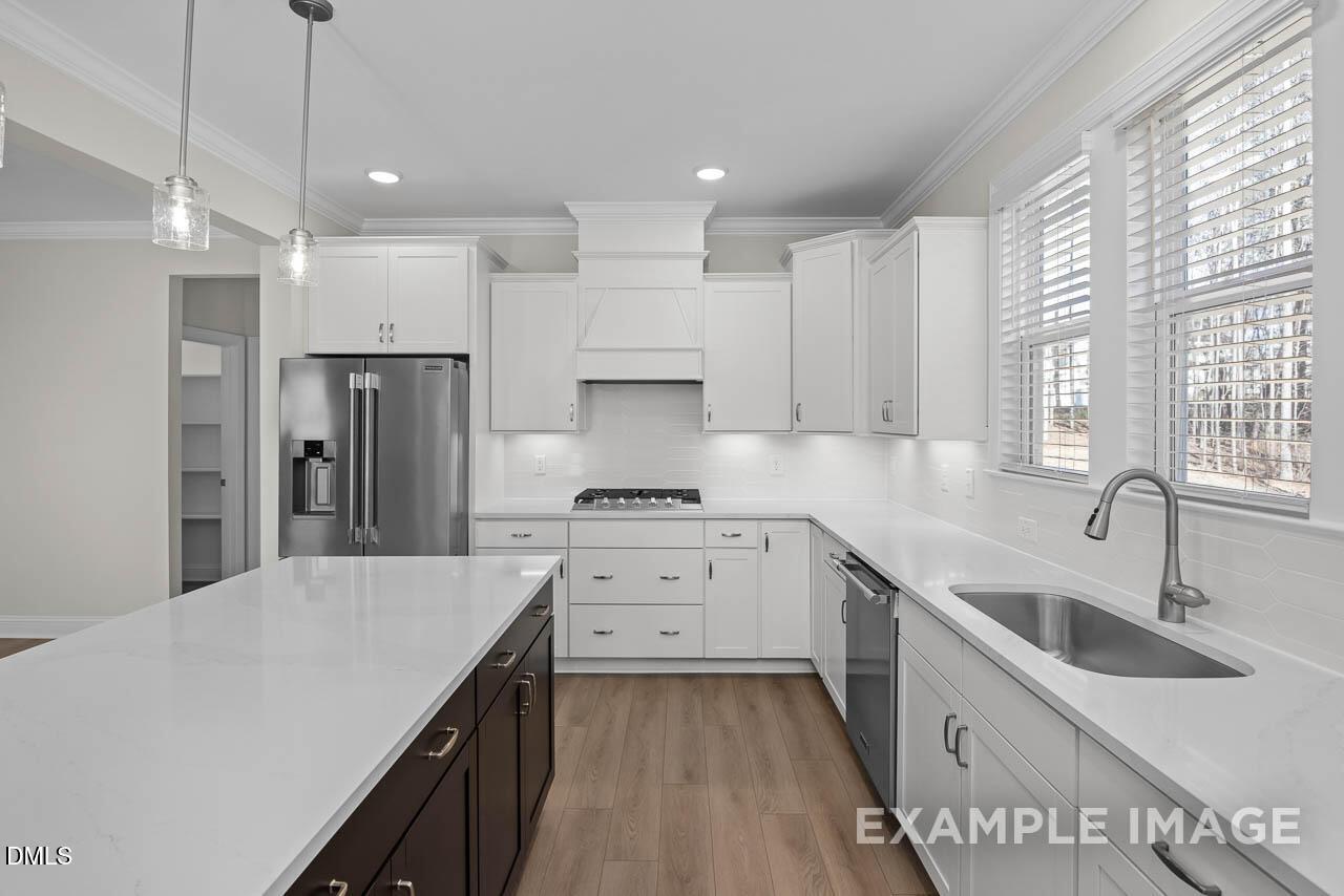Modern kitchen with white cabinets, quartz island, and stainless appliances in The Aspen C floor plan, Ashland, Apex, NC.