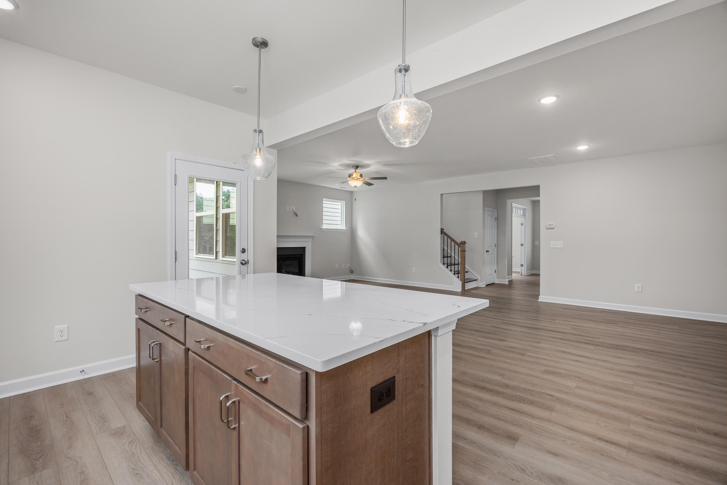 Spacious open-concept kitchen in The Aspen by Davidson Homes with white quartz island, pendant lights, and adjacent living area