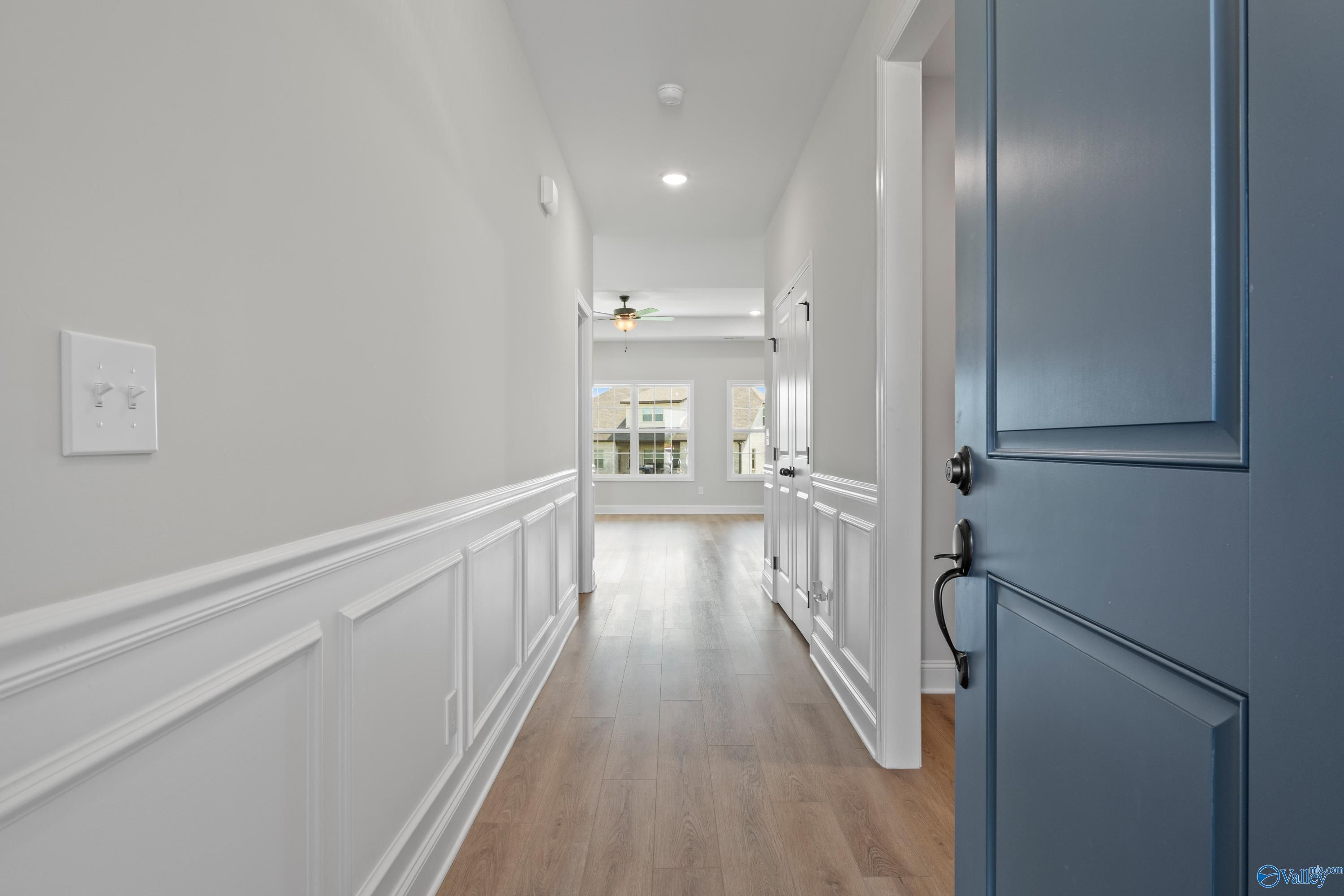 Elegant hallway with white wainscoting, hardwood floors, and ceiling fan in Davidson Homes The Rockford, Toney, Alabama