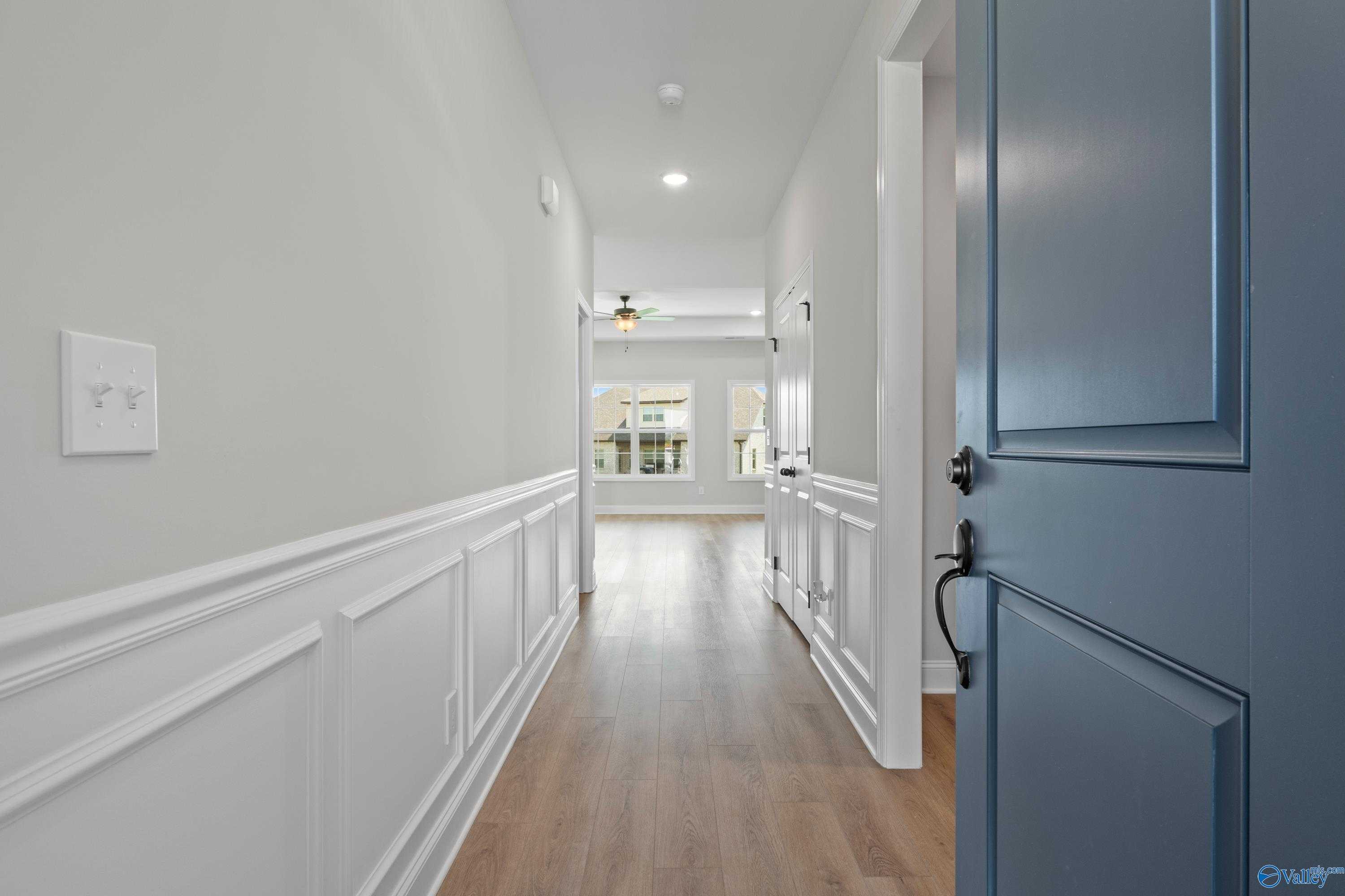 Elegant hallway with white wainscoting, hardwood floors, and ceiling fan in Davidson Homes The Rockford, Toney, Alabama