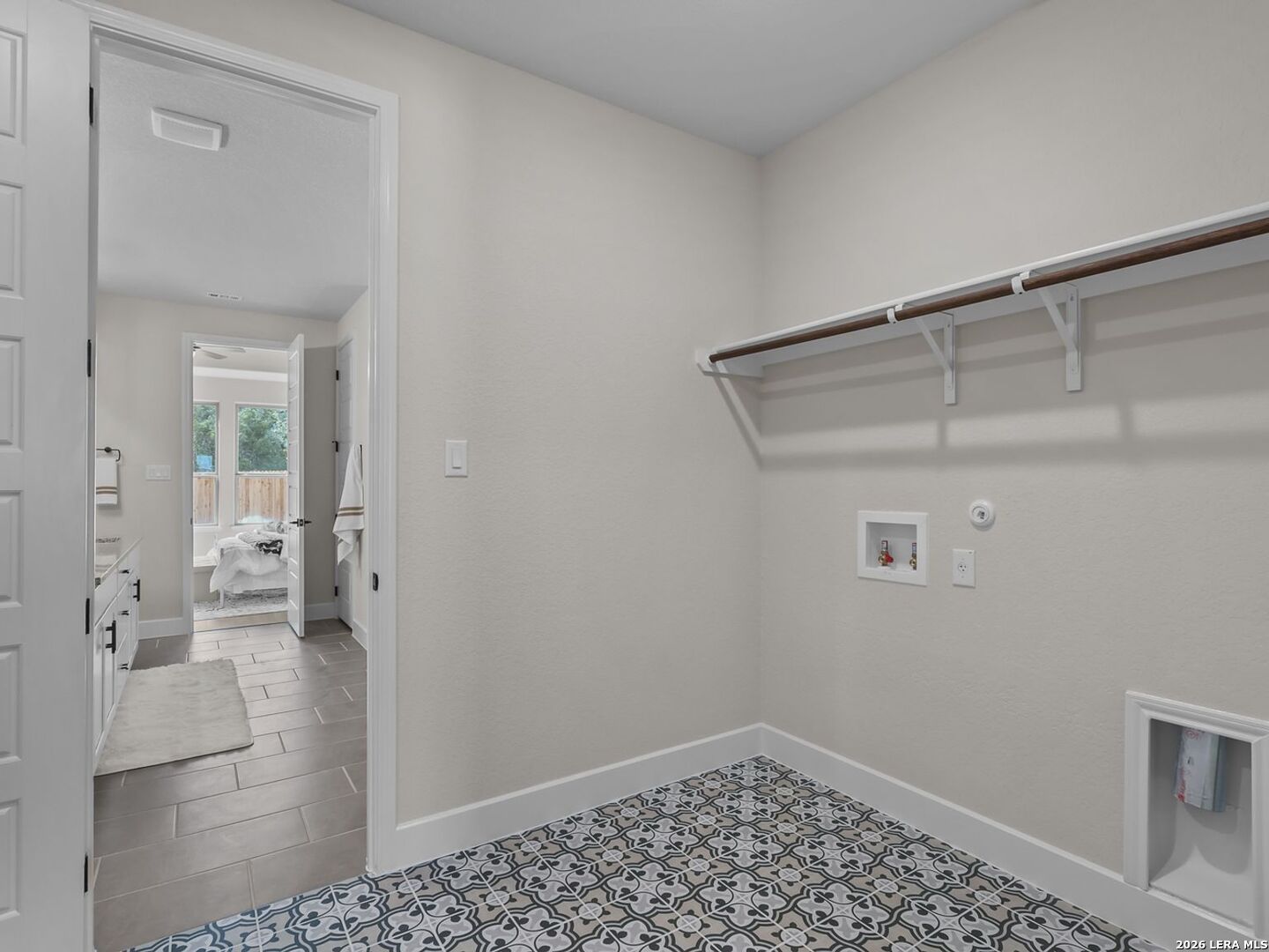 Laundry room with patterned tile flooring, shelving, and utility hookups in The Belmont H floor plan, Potranco Oaks.