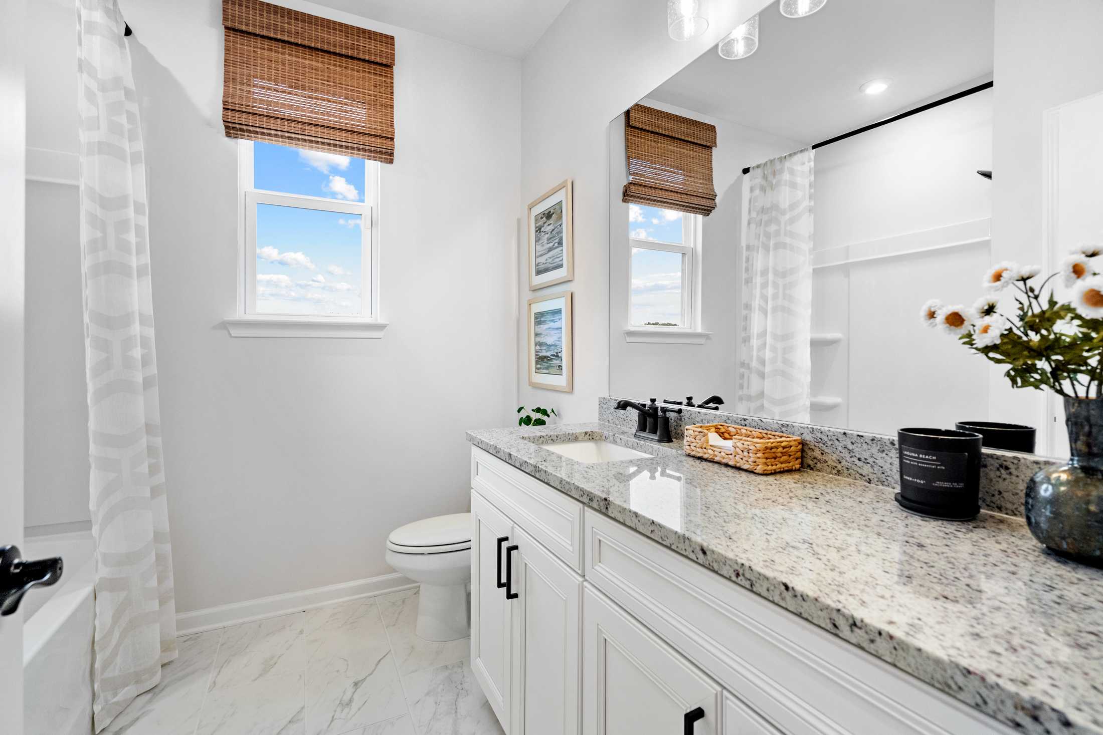 Bright master bathroom in The Edison C with white shaker vanity, granite counters, walk-in shower, and large sunny windows