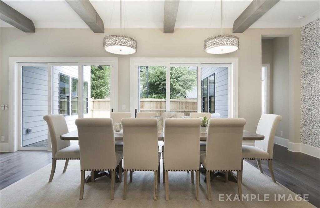 Elegant dining room featuring large wooden table, upholstered chairs, and French doors to lush backyard in The Seaside A, Woodstock, Georgia