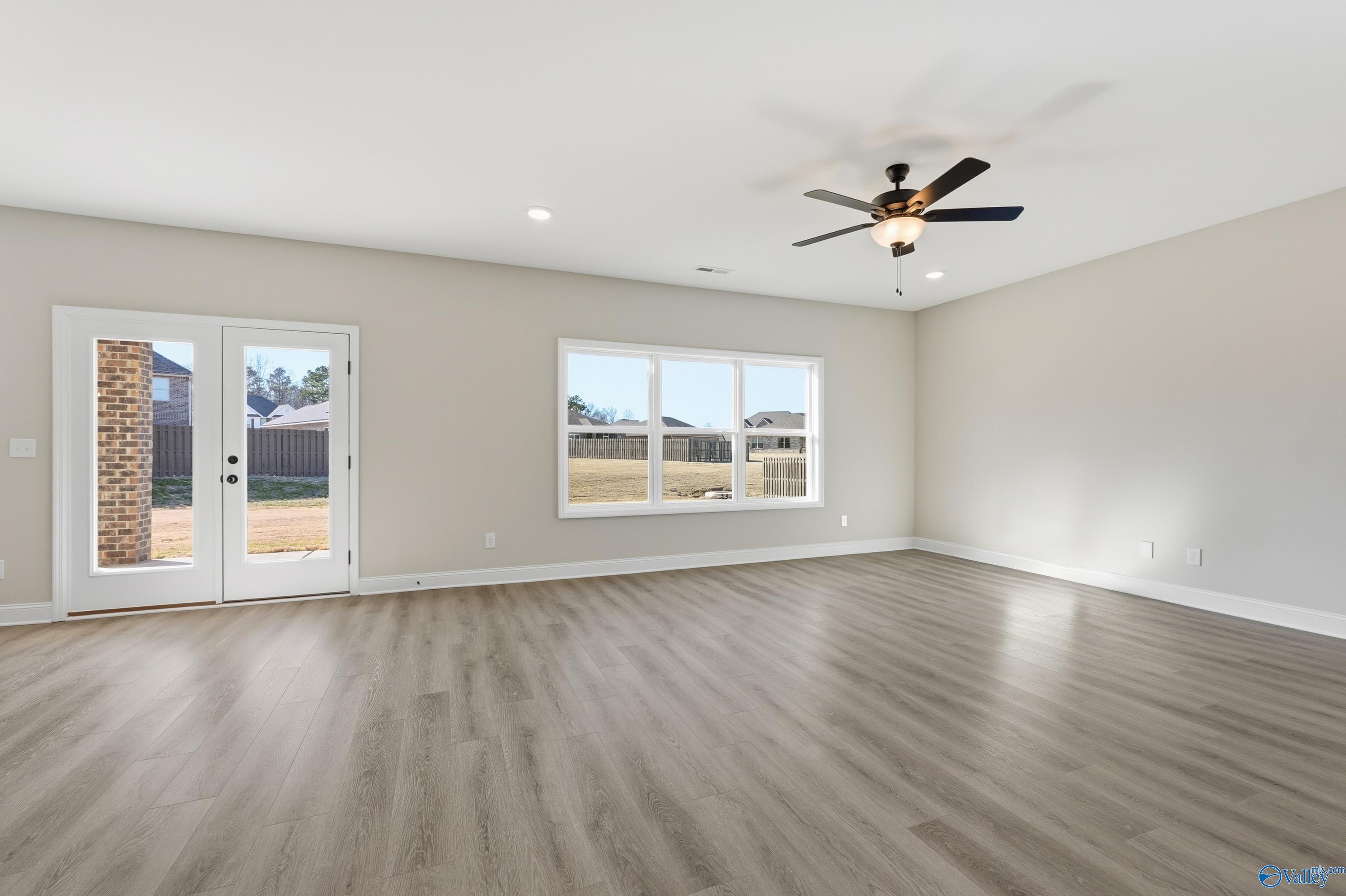 Bright living room with large windows, French doors to backyard, ceiling fan in 4-bedroom Davidson Homes Chelsea C, Harvest AL