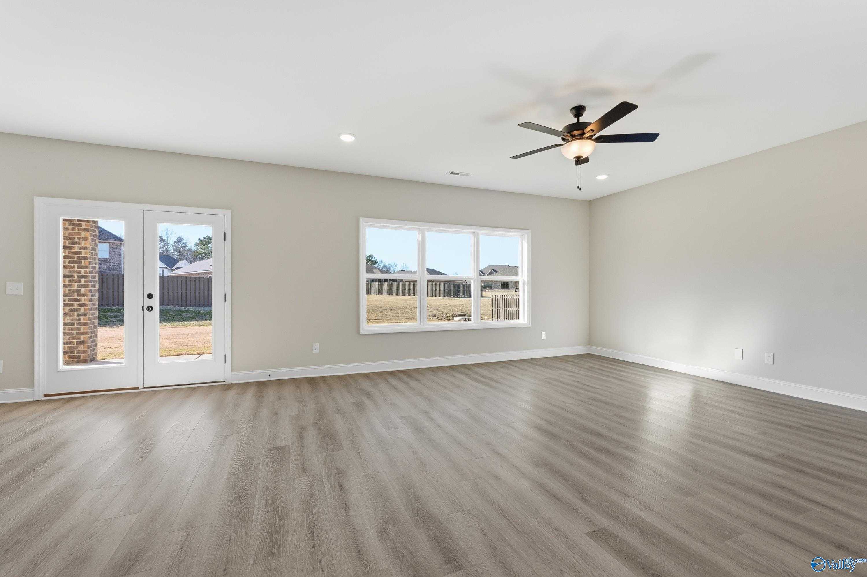 Bright living room with hardwood floors, ceiling fan, and French doors to backyard in 4-bedroom Davidson Homes Chelsea C, Harvest AL