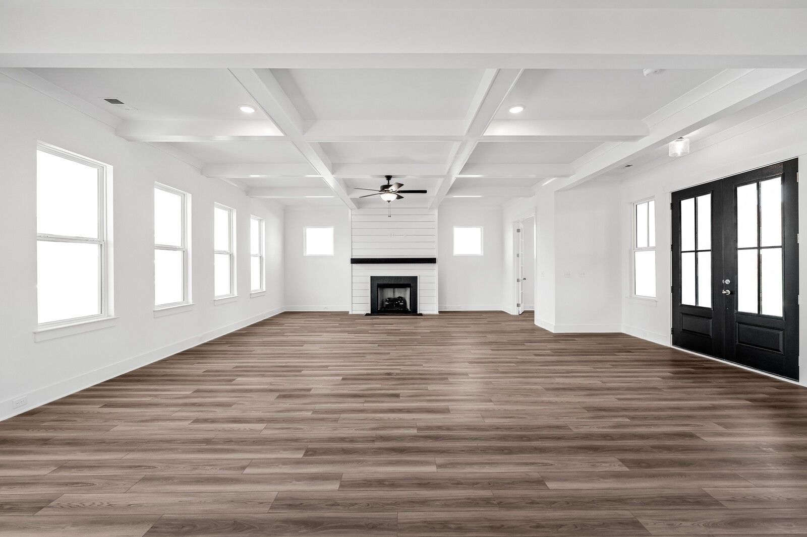 Spacious living room with beamed ceiling, ceiling fan, modern fireplace, and hardwood floors in Davidson Homes The Alston A, Murfreesboro, TN