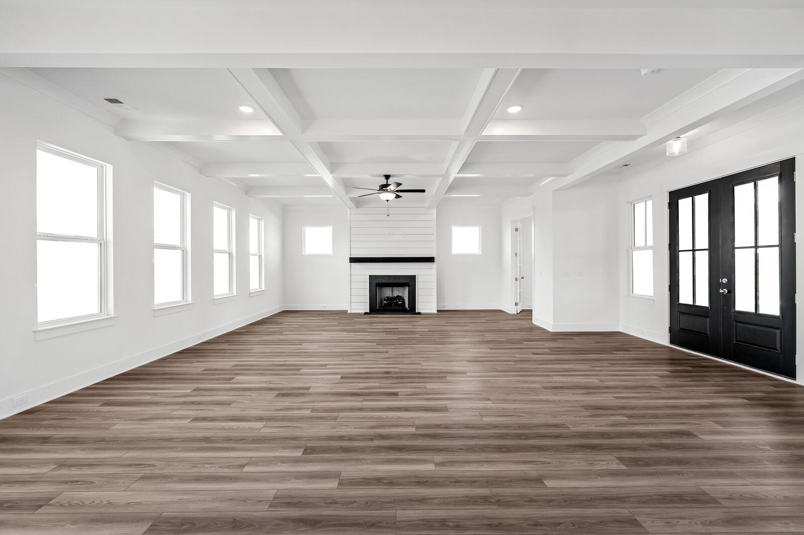 Spacious living room with beamed ceiling, ceiling fan, modern fireplace, and hardwood floors in Davidson Homes The Alston A, Murfreesboro, TN