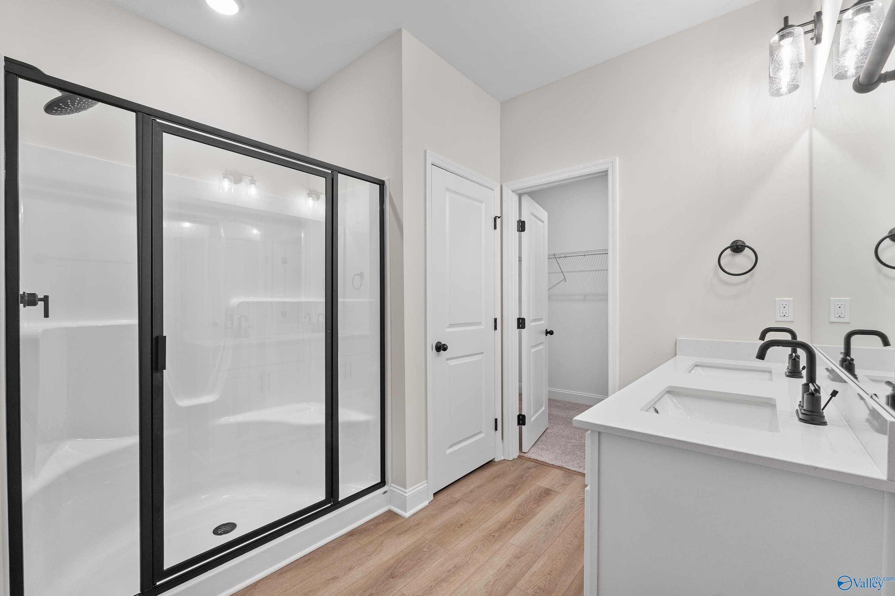 Modern master bathroom featuring frameless glass shower, double vanity, and walk-in closet in Davidson Homes The Franklin B, Hazel Green, AL