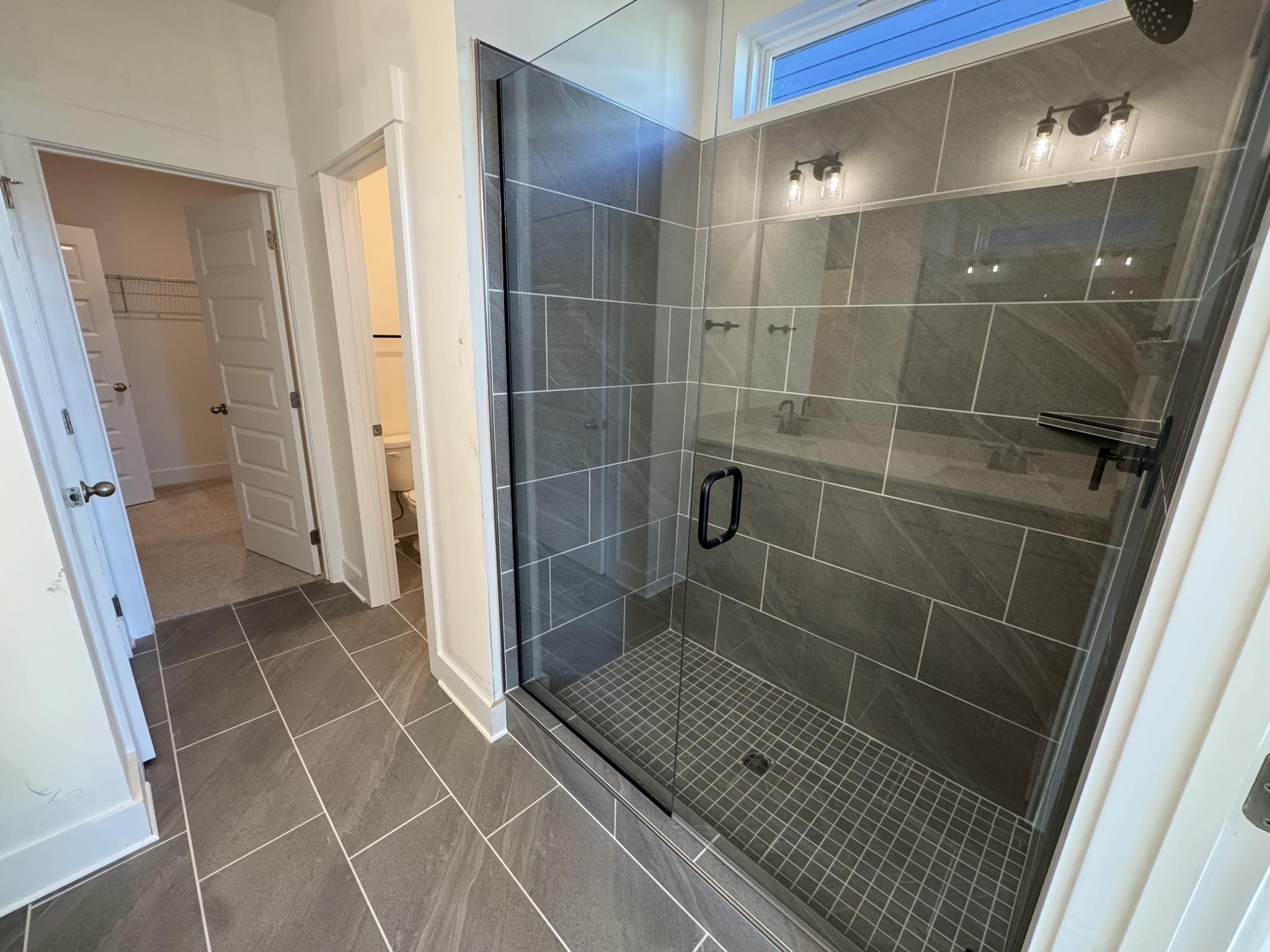 Modern master bathroom featuring frameless glass walk-in shower with gray tile in Davidson Homes The Ash A, Gallatin, Tennessee