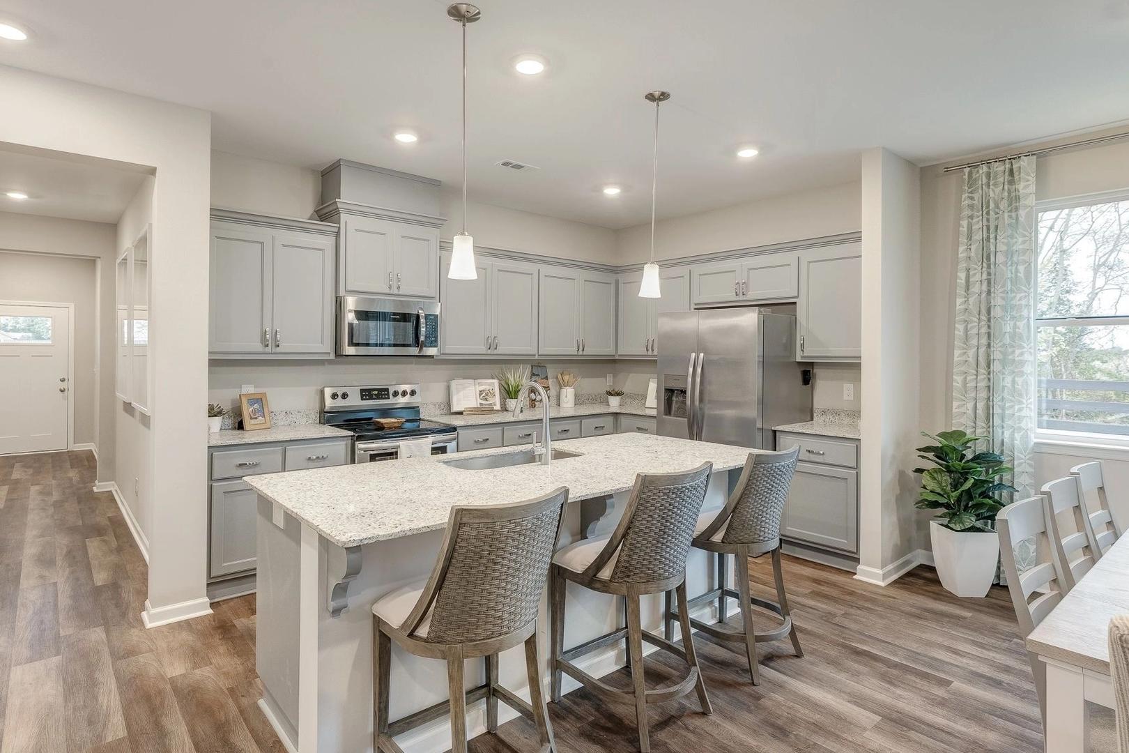 Spacious modern kitchen with gray shaker cabinets, white quartz island, bar seating, stainless appliances in Carroll Green Harvest AL