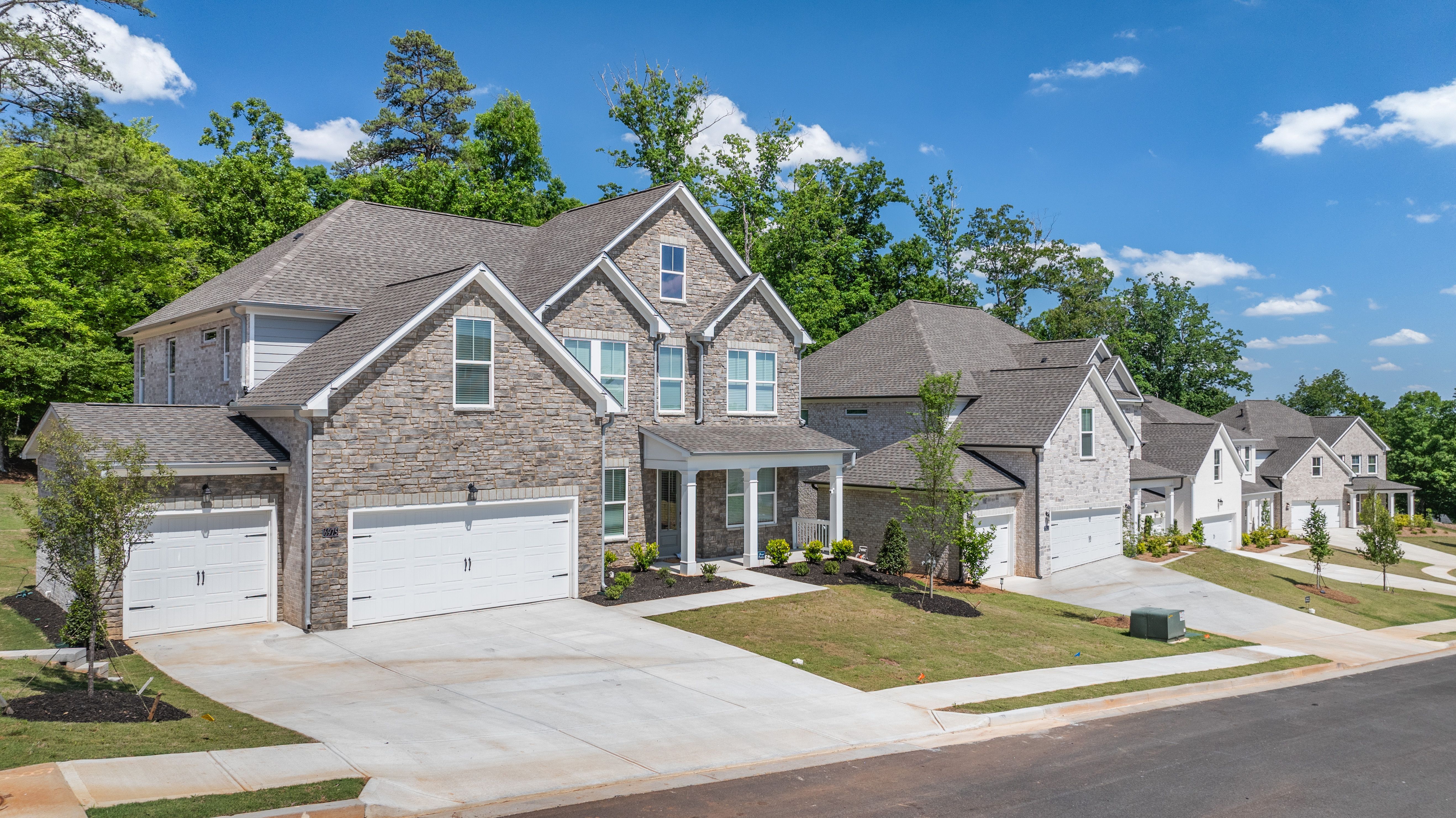 Stone exterior homes at Melody Lakeside Estates in Buford, GA, built by Davidson Homes with attached garages.