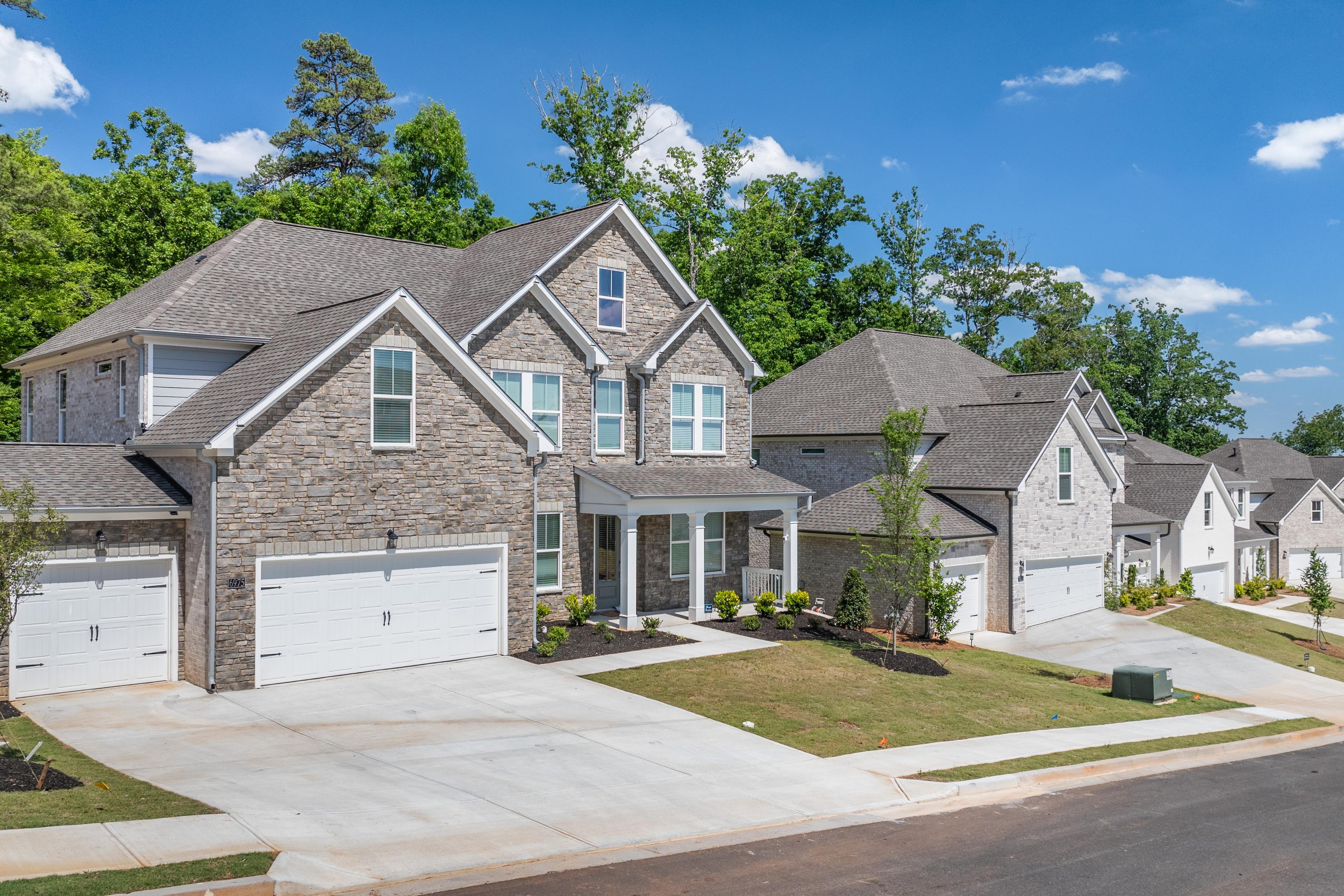 Stone exterior homes at Melody Lakeside Estates in Buford, GA, built by Davidson Homes with attached garages.