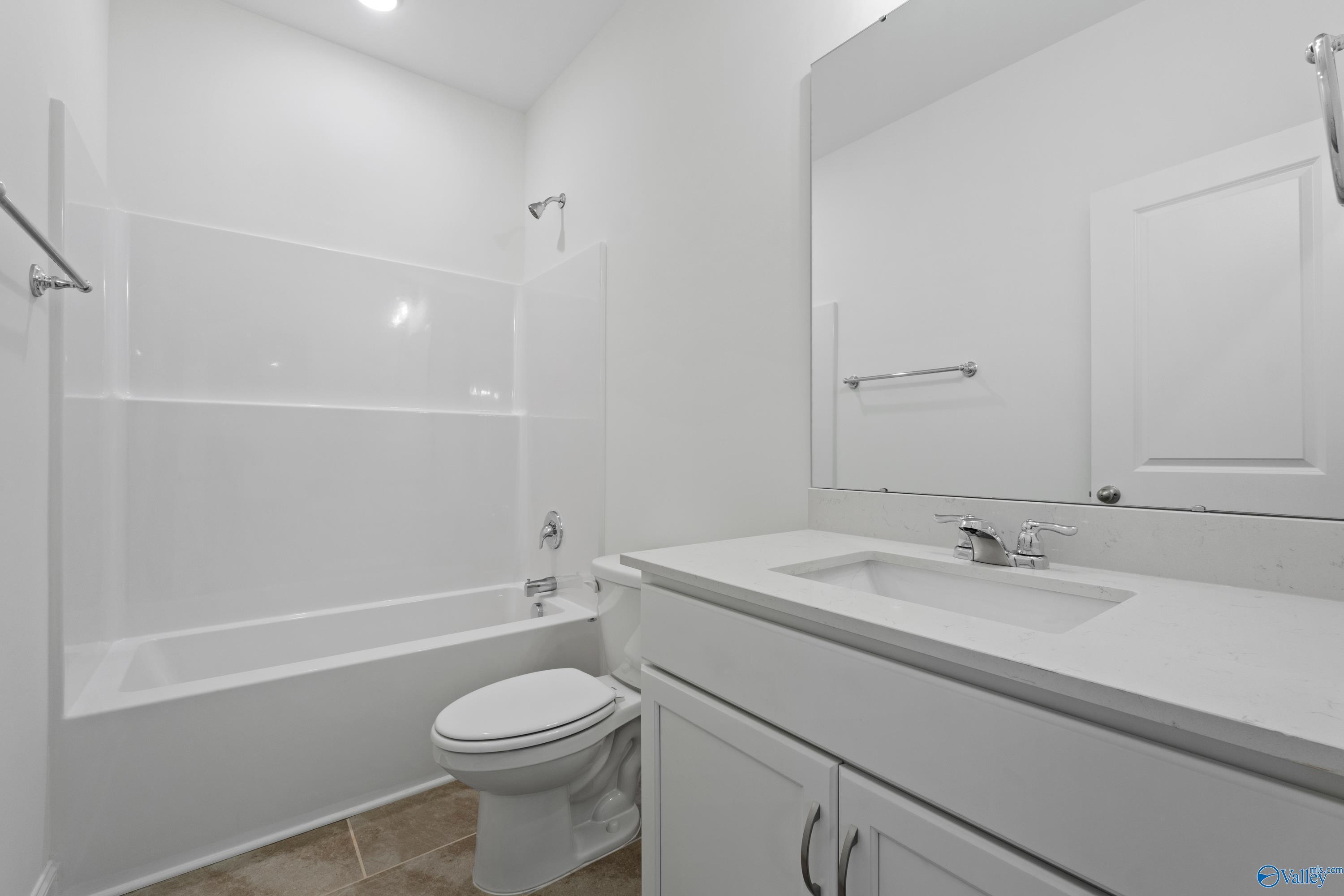 Bright white guest bathroom with bathtub-shower combo, single vanity sink, and toilet in Davidson Homes The Oxford, Creekside, Harvest, Alabama