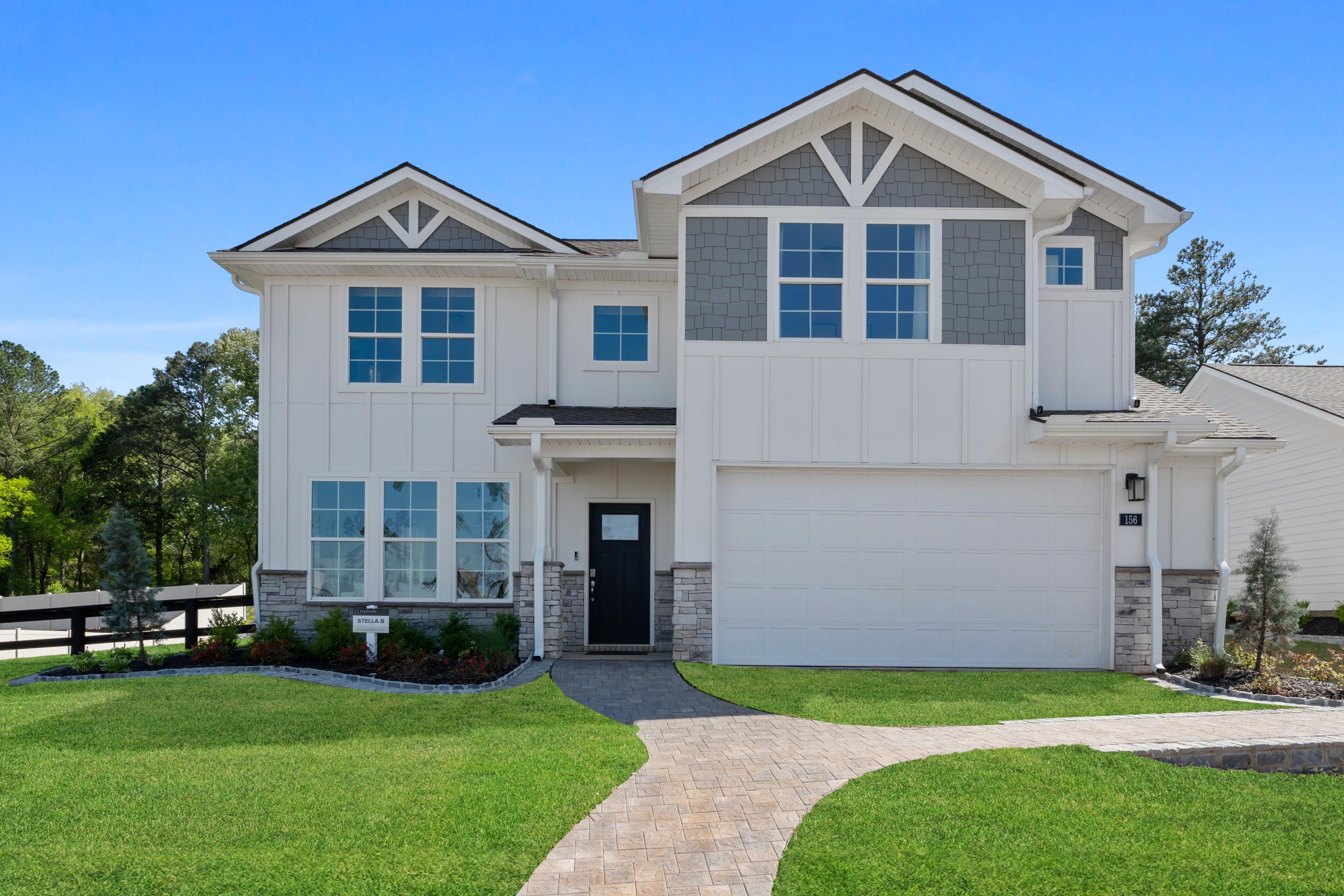 Two-story modern farmhouse home exterior at Evergreen Mill in Madison Alabama with white siding covered porch and landscaped yard