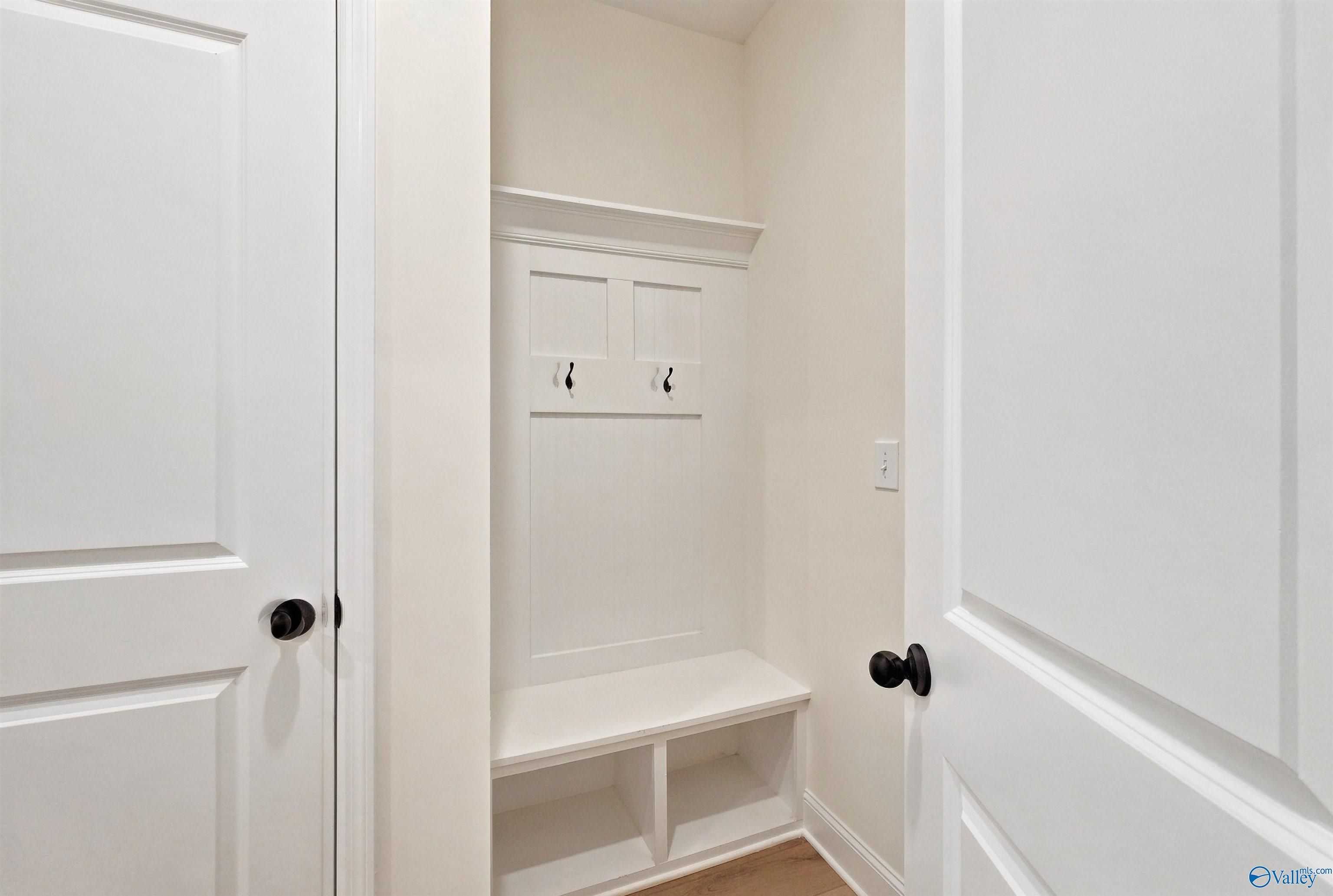 White mudroom bench with coat hooks and storage cubbies in The Chelsea C home by Davidson Homes, New Market, Alabama.