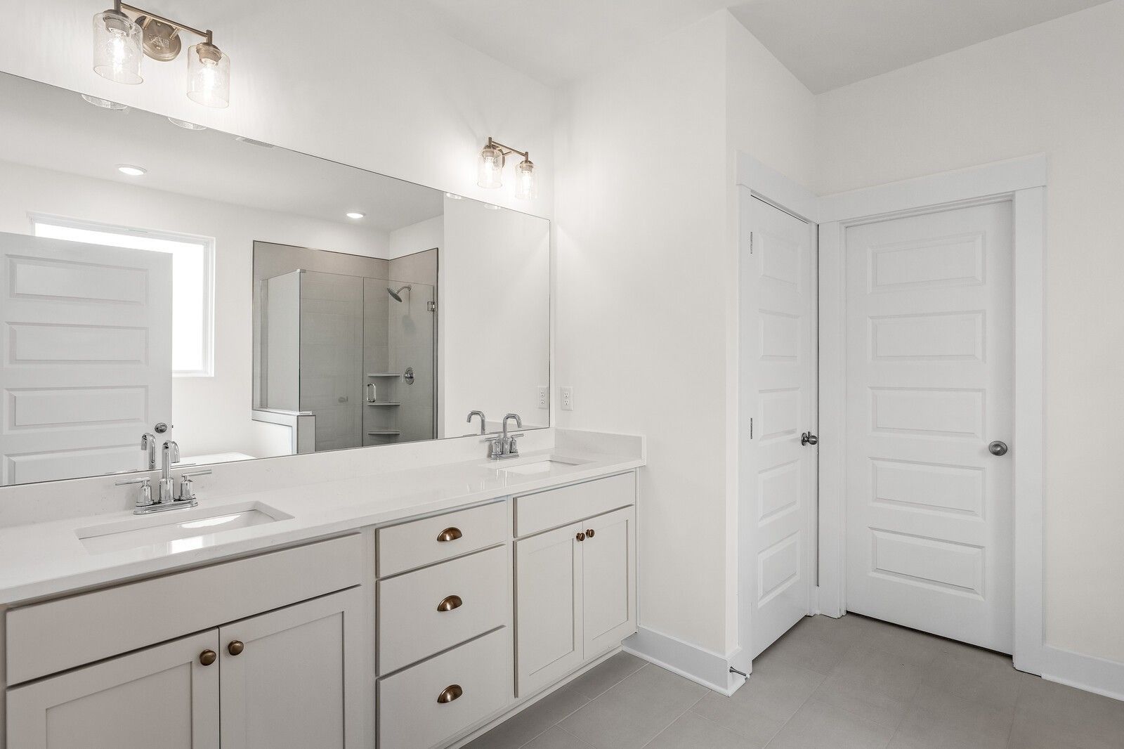 Modern master bathroom featuring double vanity, quartz counters, and glass shower in Davidson Homes Ridgeport, Gallatin, TN