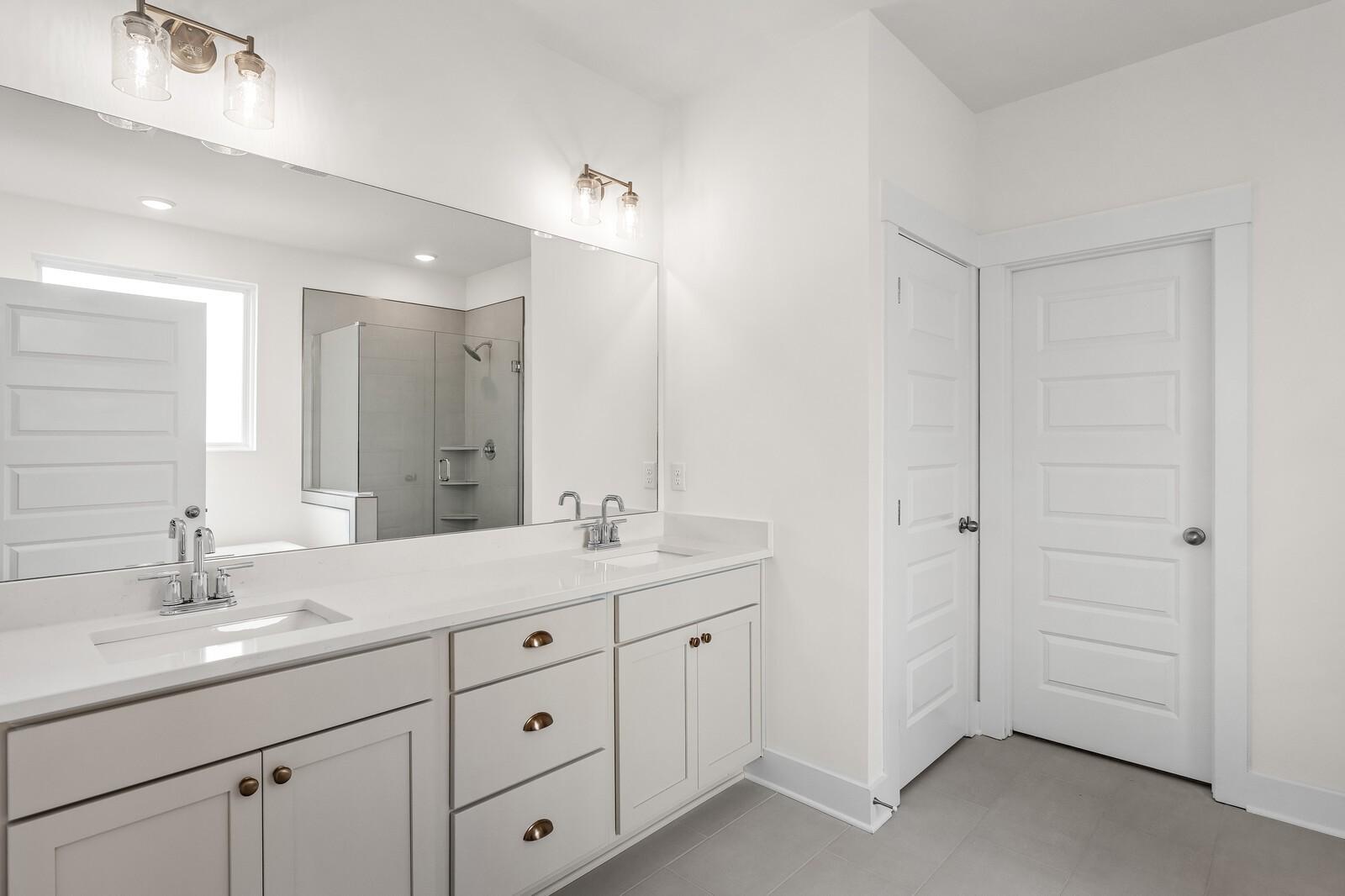 Modern master bathroom featuring double vanity, quartz counters, and glass shower in Davidson Homes Ridgeport, Gallatin, TN