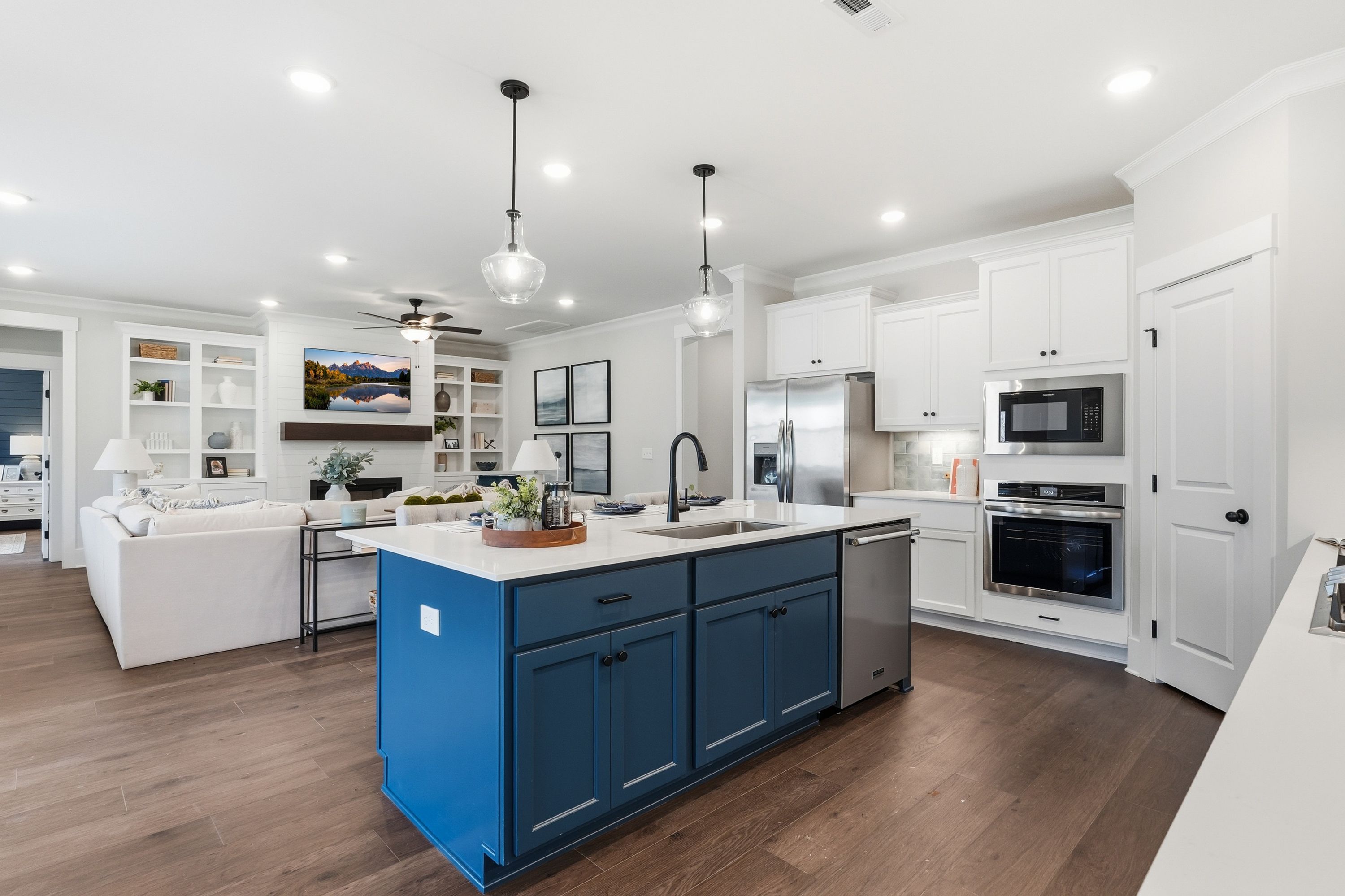 Spacious open-concept kitchen at Noble Ridge in Cullman Alabama with blue island, white cabinets, stainless appliances, hardwood floors