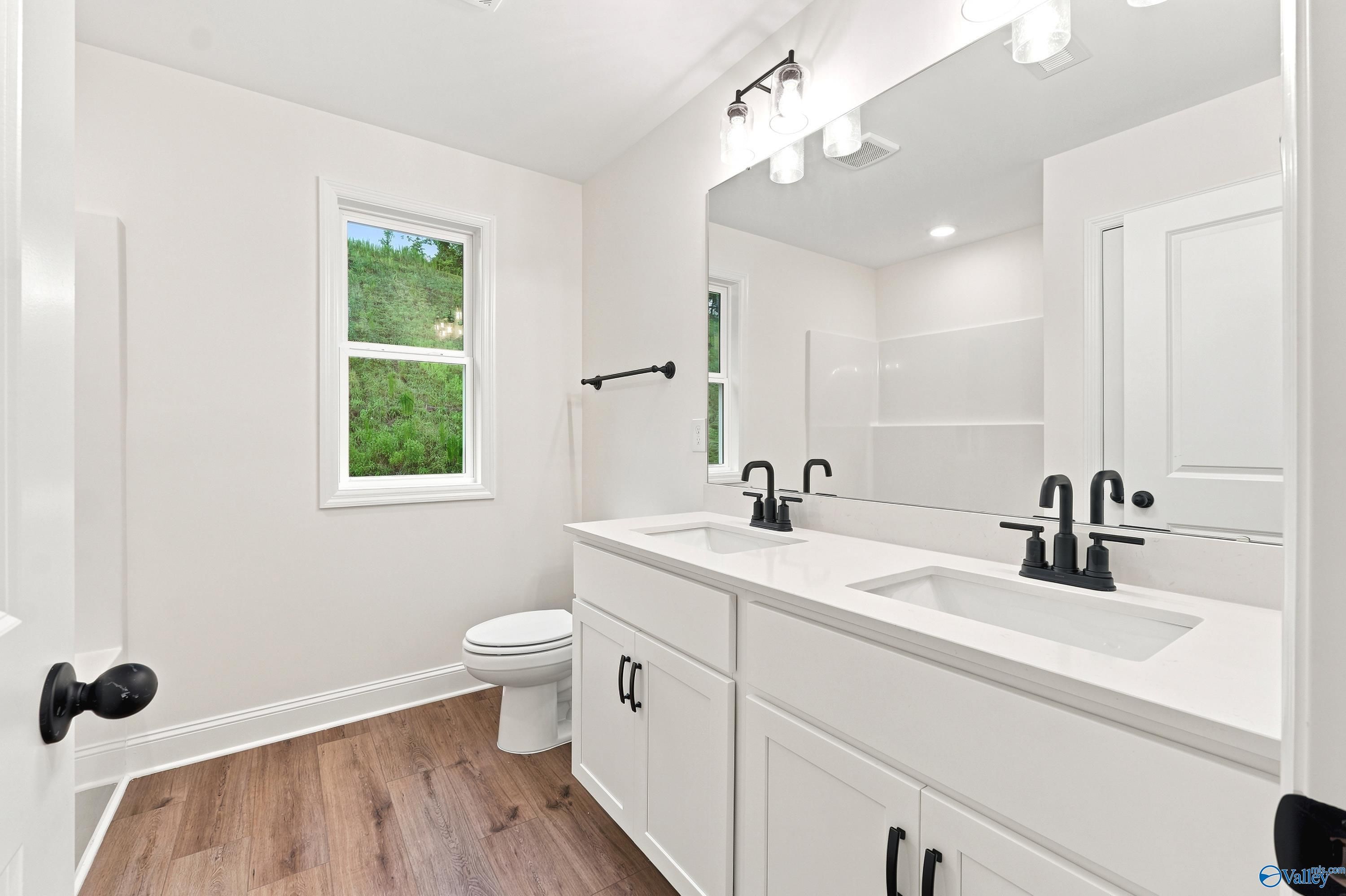 Modern bathroom with dual vanity, white cabinets, and matte black fixtures in The Shelby D home at Noble Ridge, Cullman, AL.
