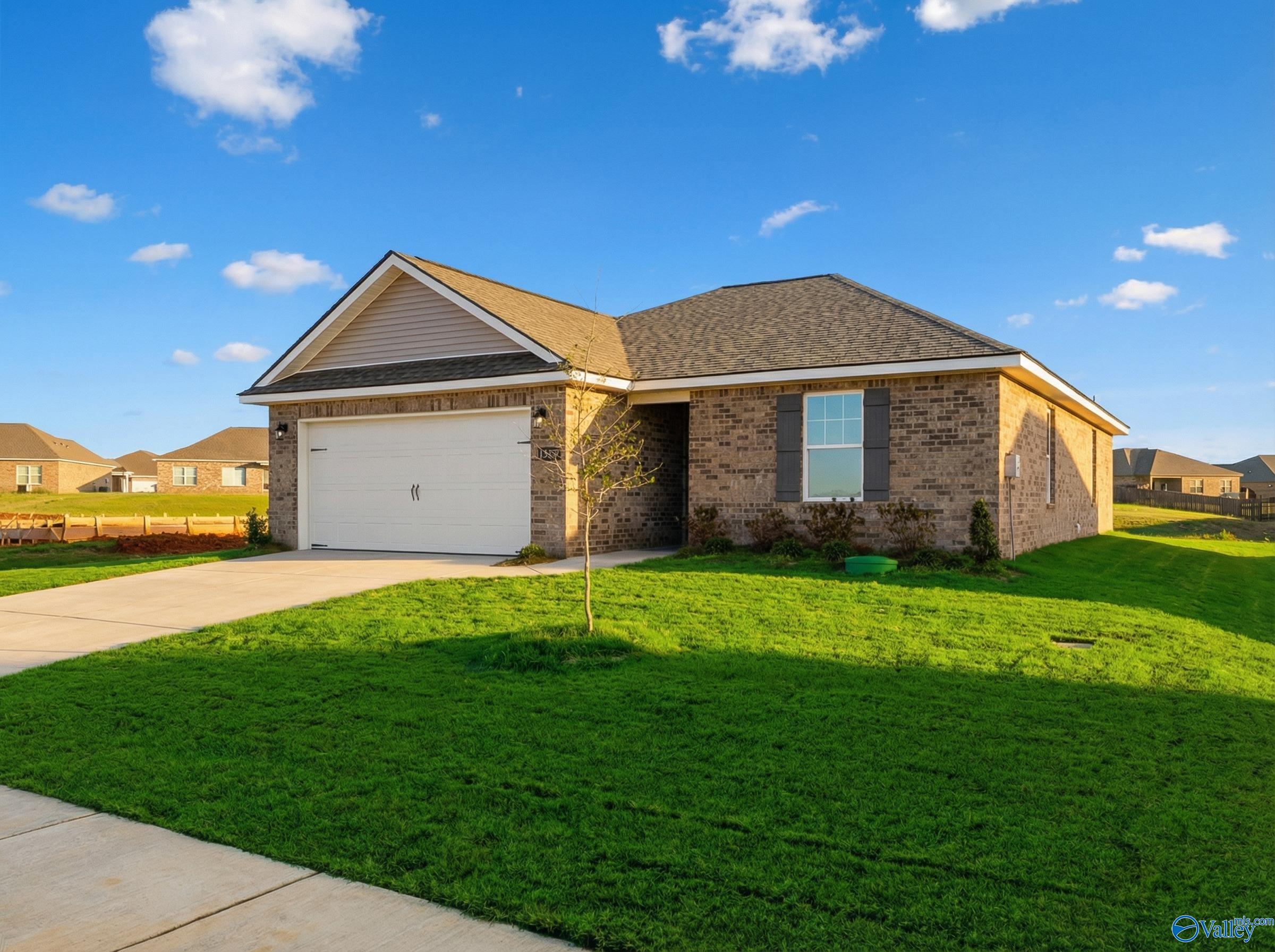 Modern 1-story brick home with 2-car garage, driveway, and lush green lawn in Heritage Lakes, New Market, Alabama by Davidson Homes The Butler