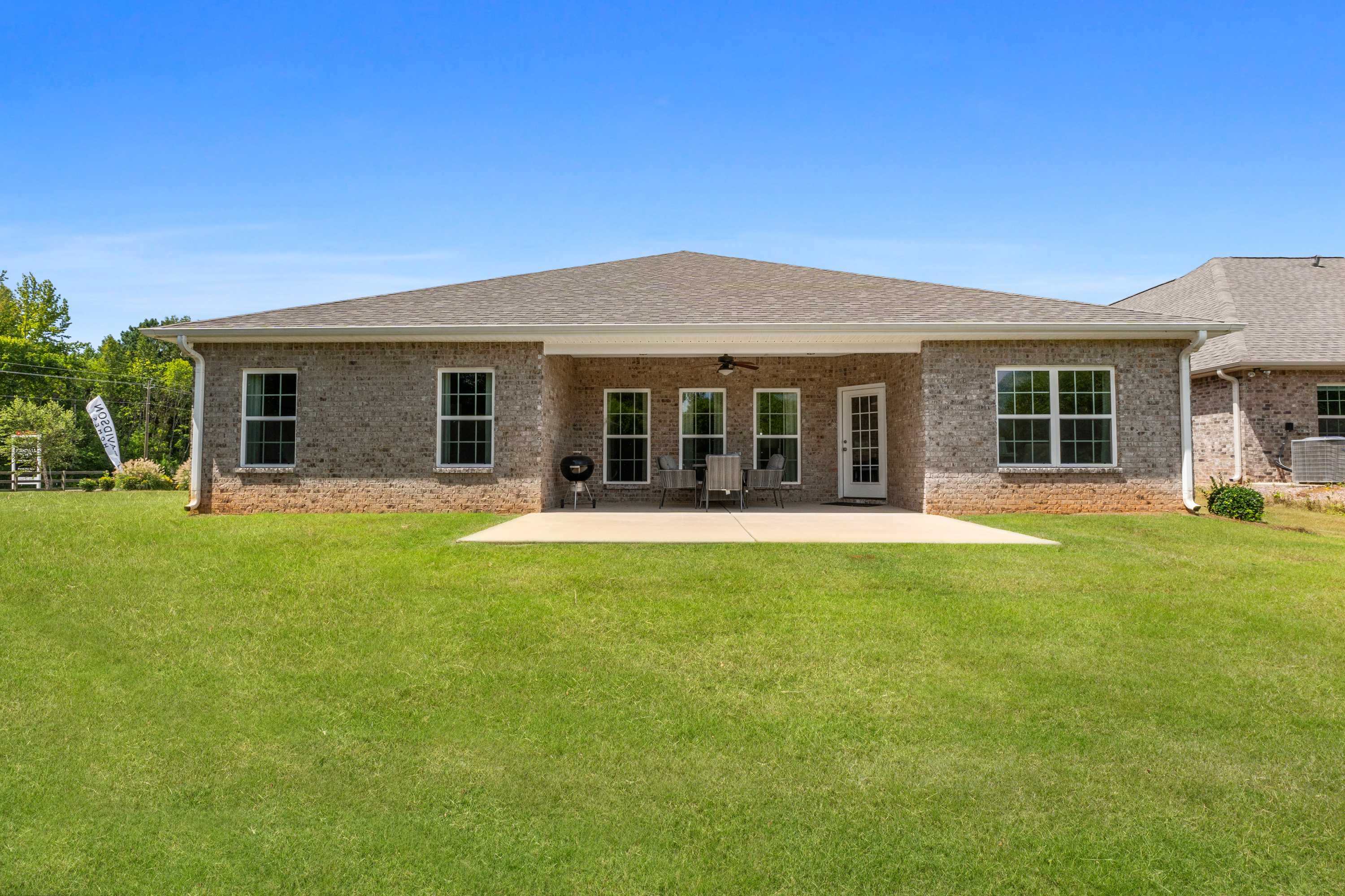 Rear view of single-story brick home at Kendall Downs in Toney Alabama with covered patio French doors and lush lawn