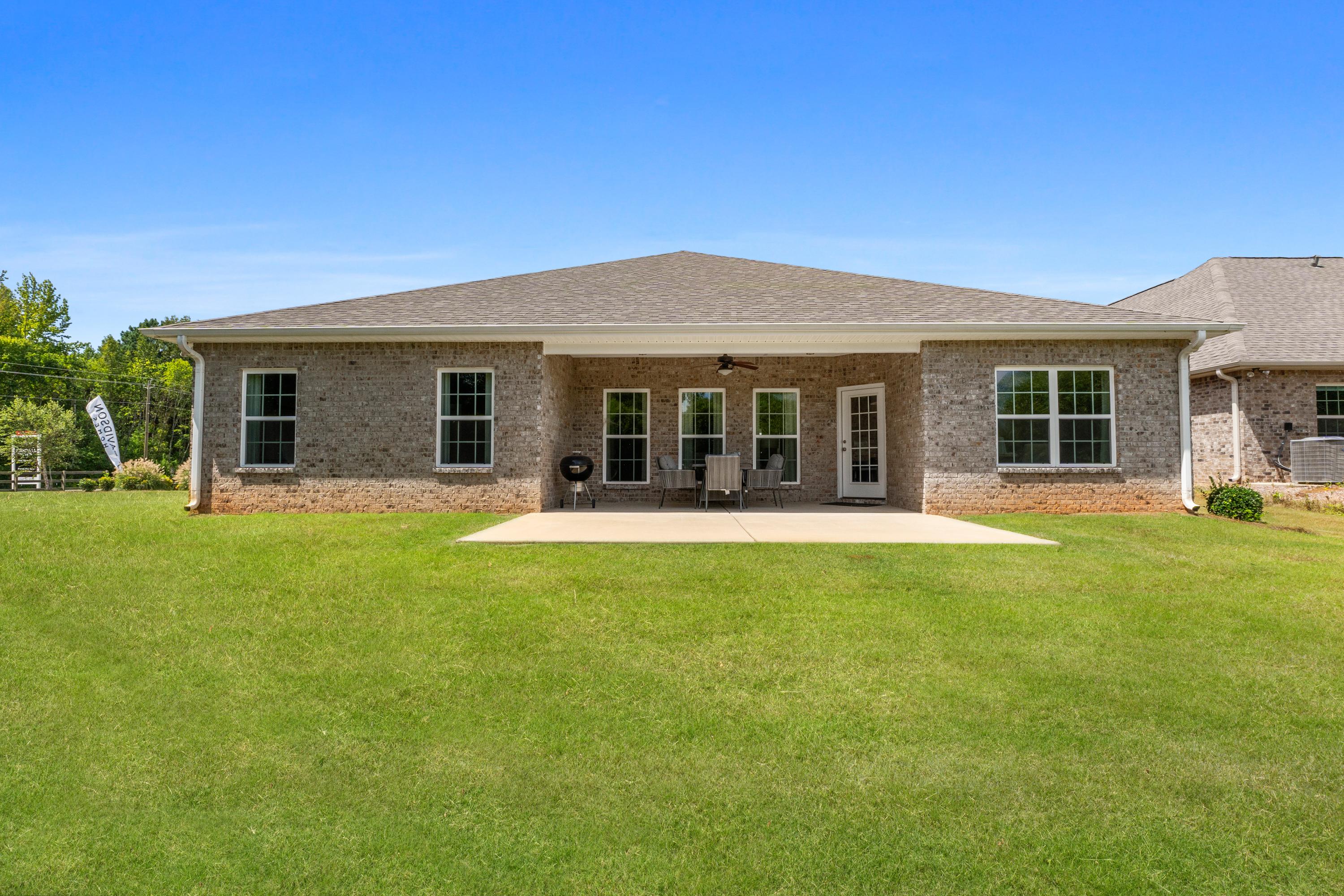 Rear view of single-story brick home at Kendall Downs in Toney Alabama with covered patio French doors and lush lawn