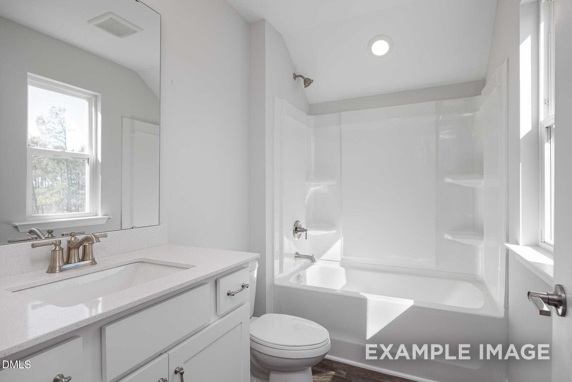 Bright bathroom featuring white vanity, soaking tub, and walk-in shower in 4-bedroom Davidson Homes The Cypress B II, Angier, NC