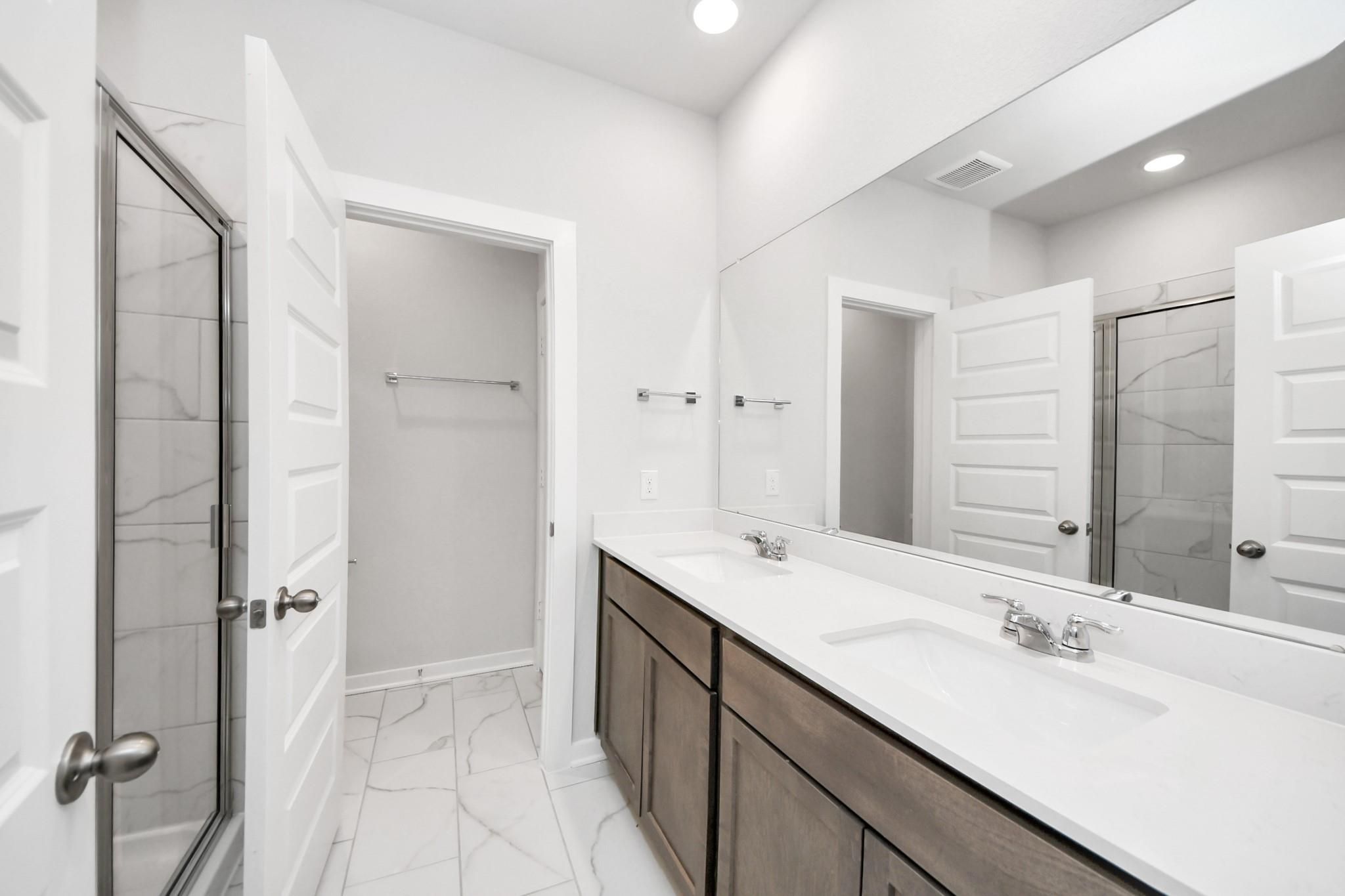 Modern bathroom with dual vanity and glass-enclosed shower in The Sabine E floor plan at Liberty Estates, Cleveland, Texas.
