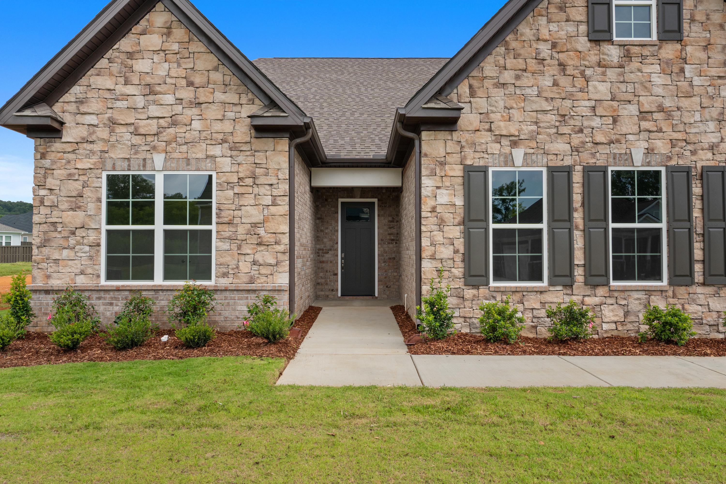 Front elevation of The Oxford 2-story craftsman home with stone facade, dark shutters, and landscaped walkway