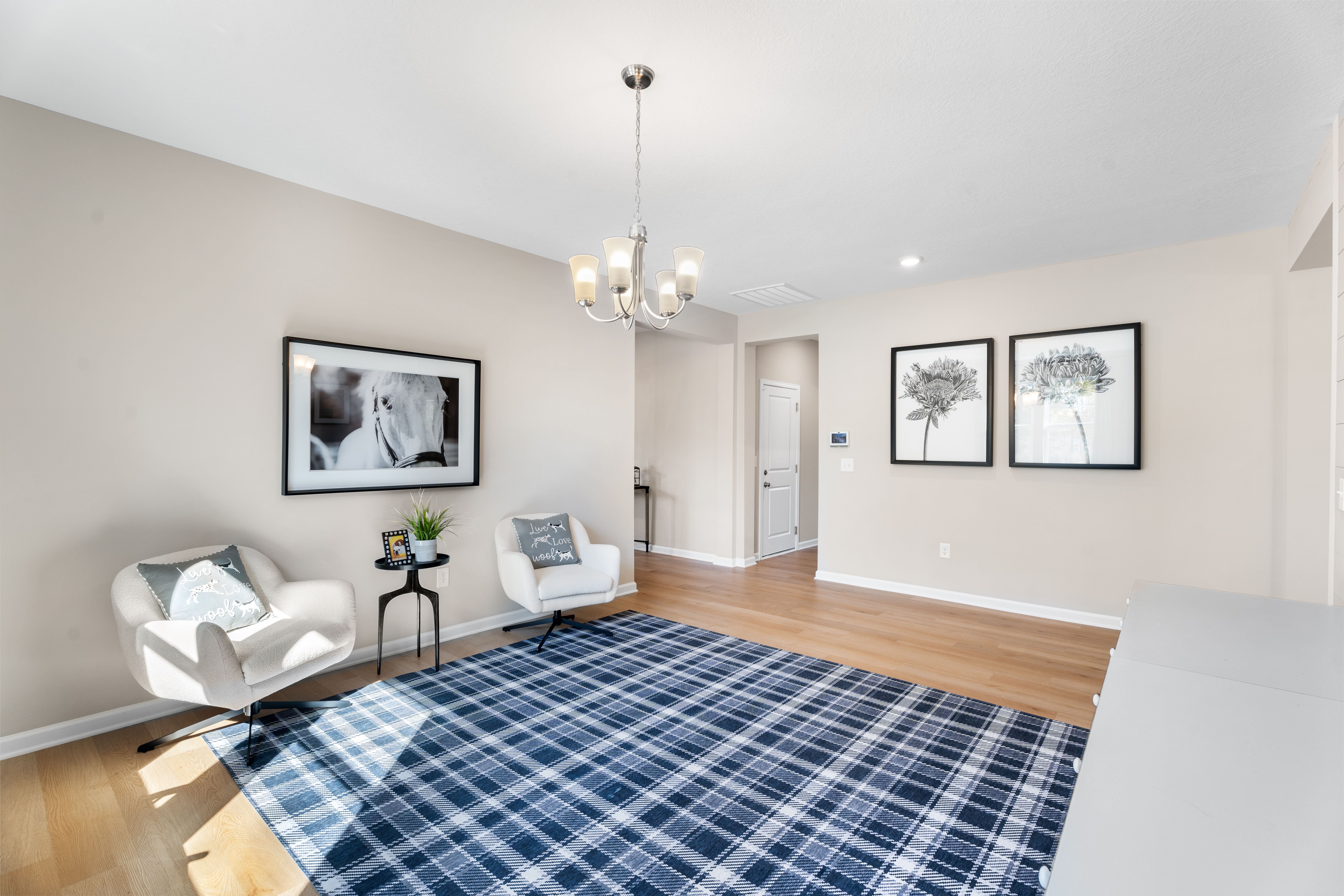 Cozy home office in Silver Oak Cusseta Alabama by Evermore Homes with white desk, plaid rug, shiplap walls, and armchairs