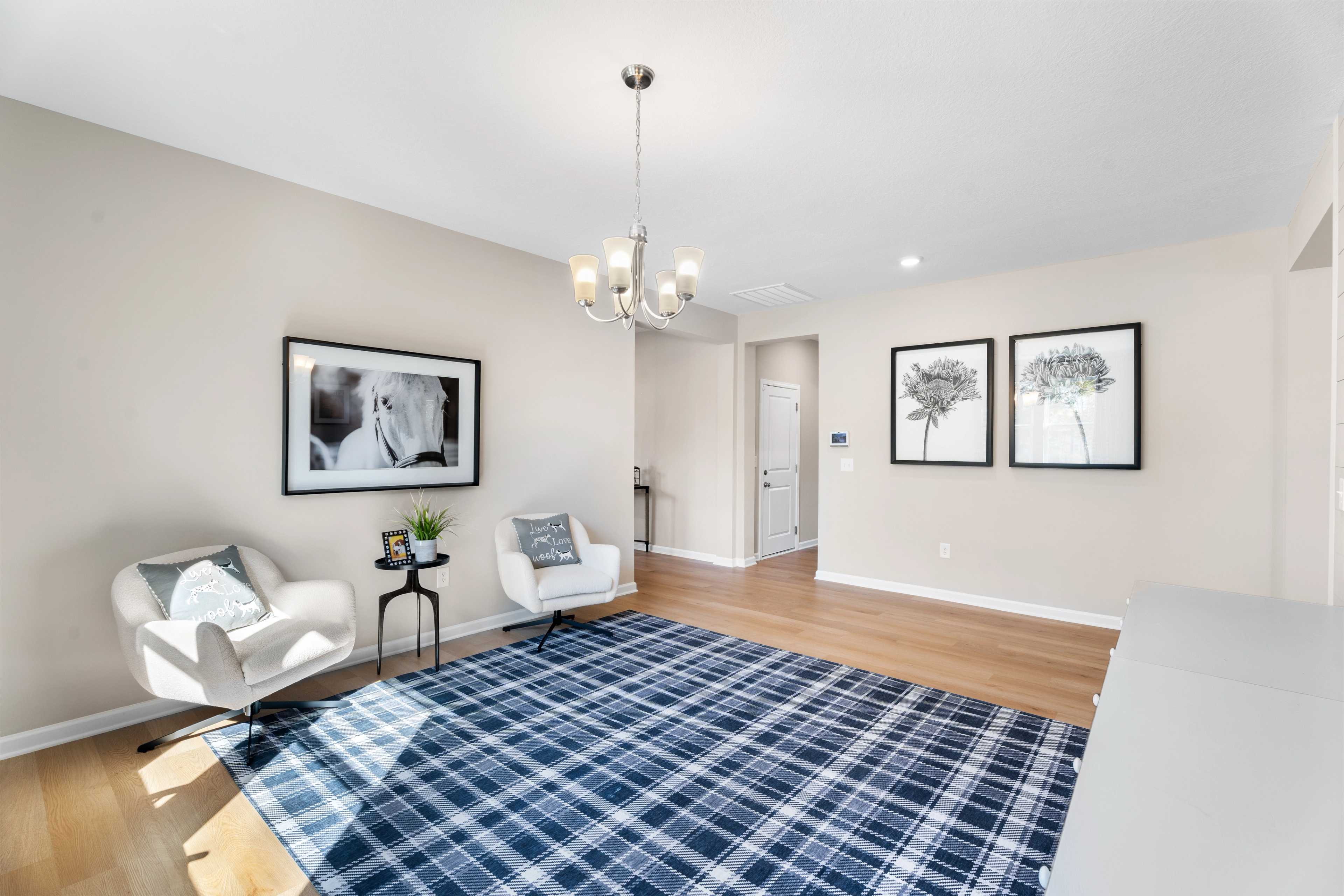 Cozy home office in Silver Oak Cusseta Alabama by Evermore Homes with white desk, plaid rug, shiplap walls, and armchairs