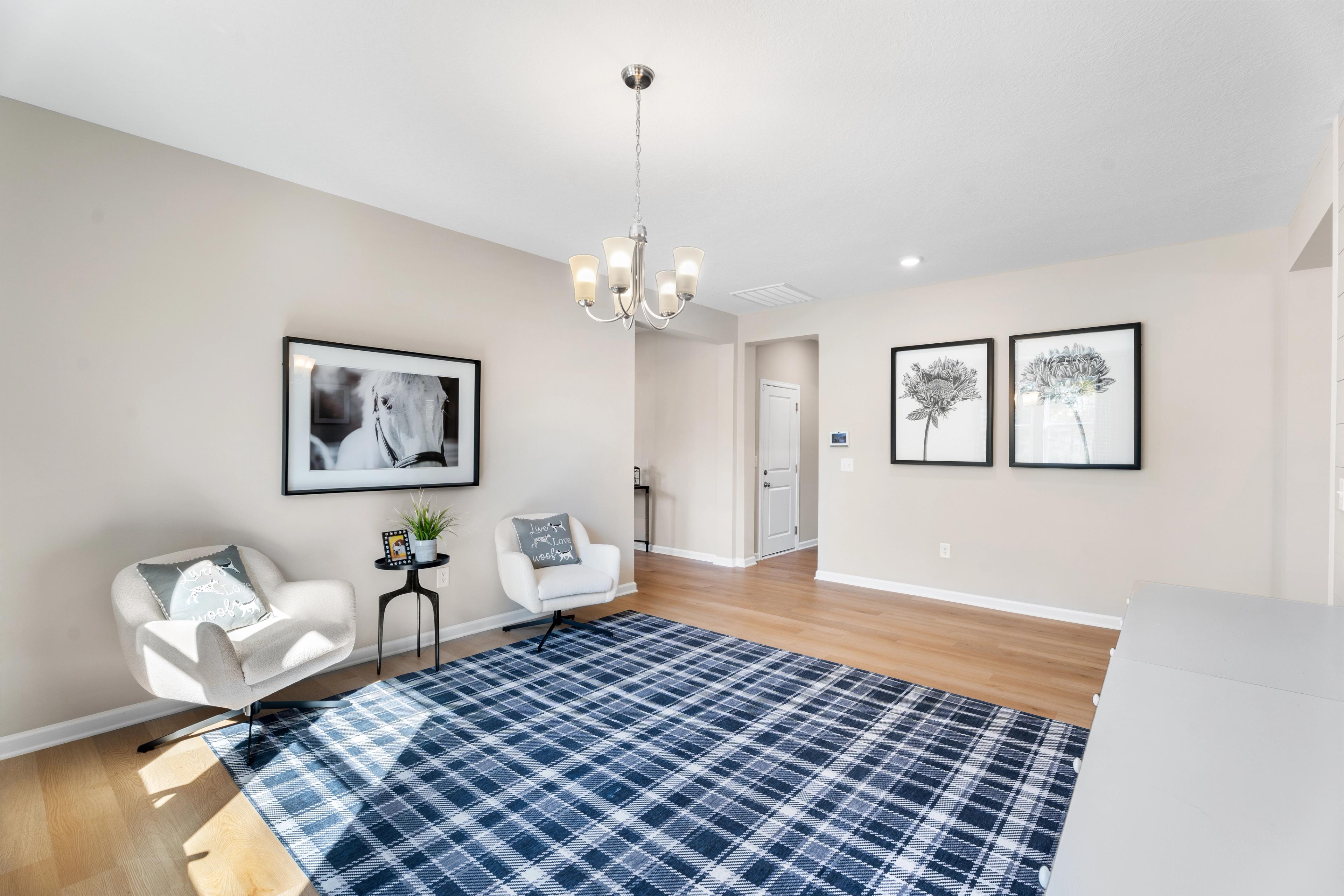 Cozy home office in Silver Oak Cusseta Alabama by Evermore Homes with white desk, plaid rug, shiplap walls, and armchairs