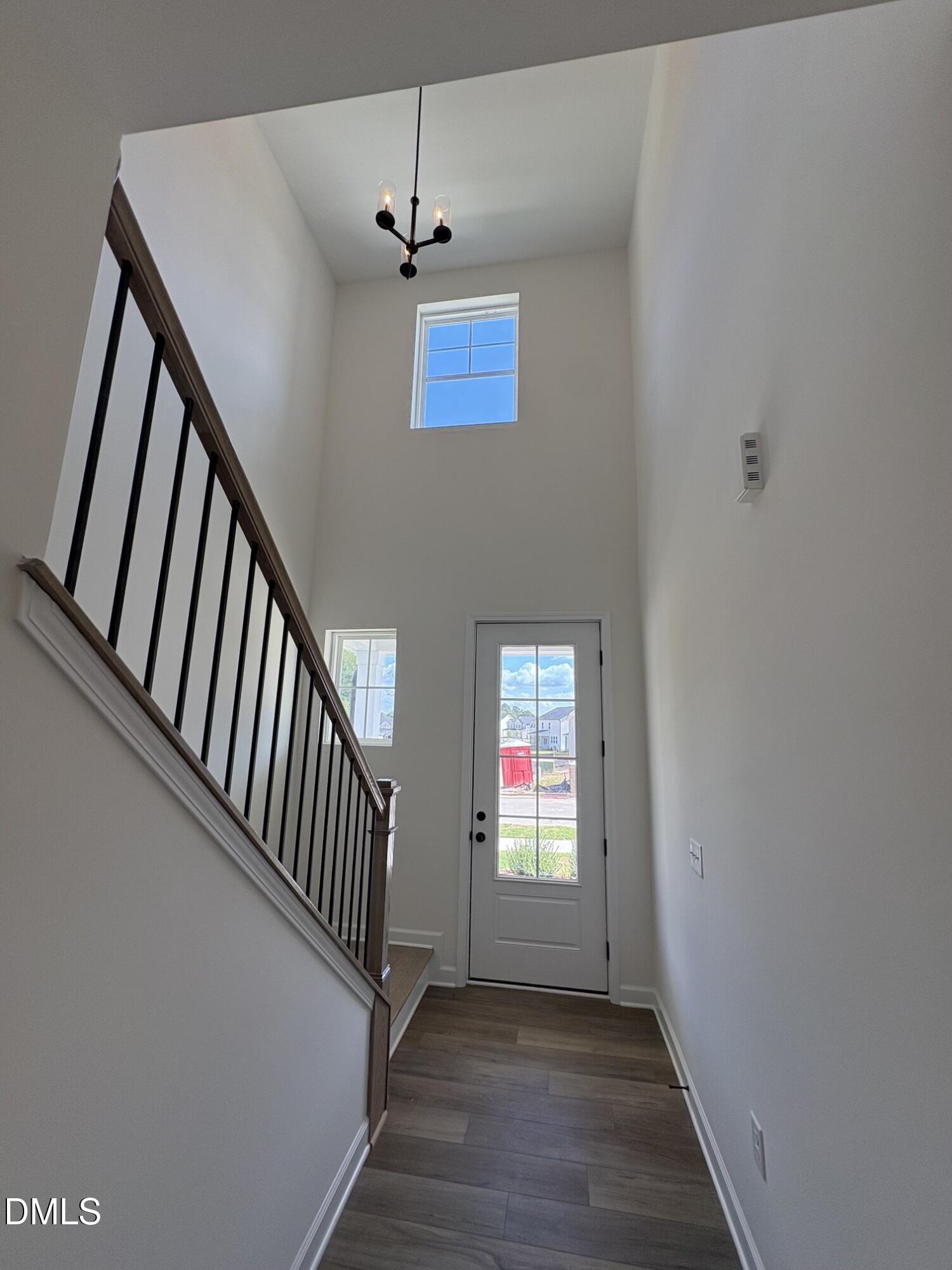 Two-story foyer with glass-panel front door, staircase with wrought iron balusters, and hardwood floors in Davidson Homes Adalynn A plan