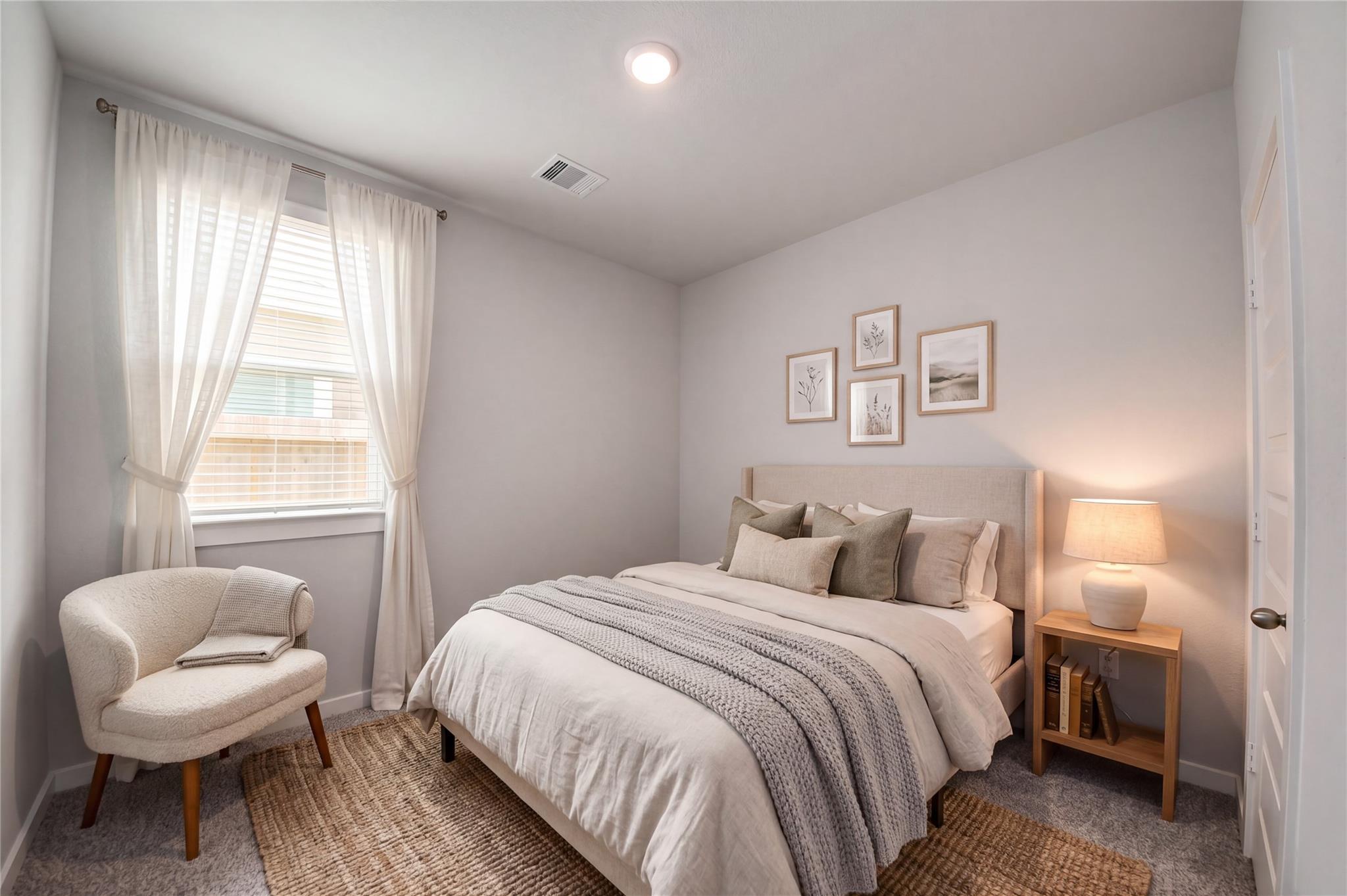 Bright bedroom with upholstered bed, accent chair, and natural light in The Frio F by Davidson Homes, Robins Landing, Houston.