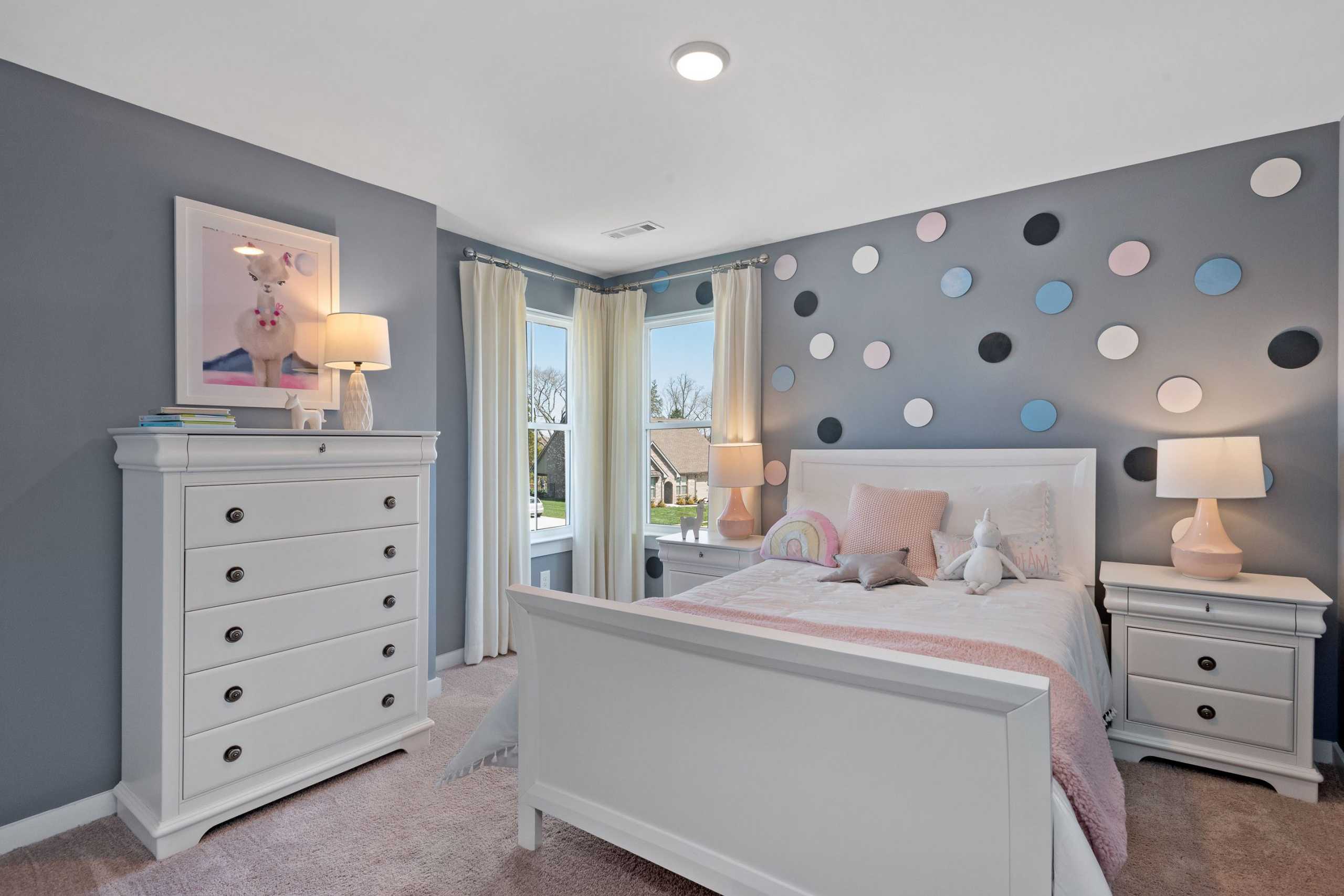 Charming girl's bedroom at Rivers Edge in Murfreesboro TN with polka dot walls, white bed, and pink accents