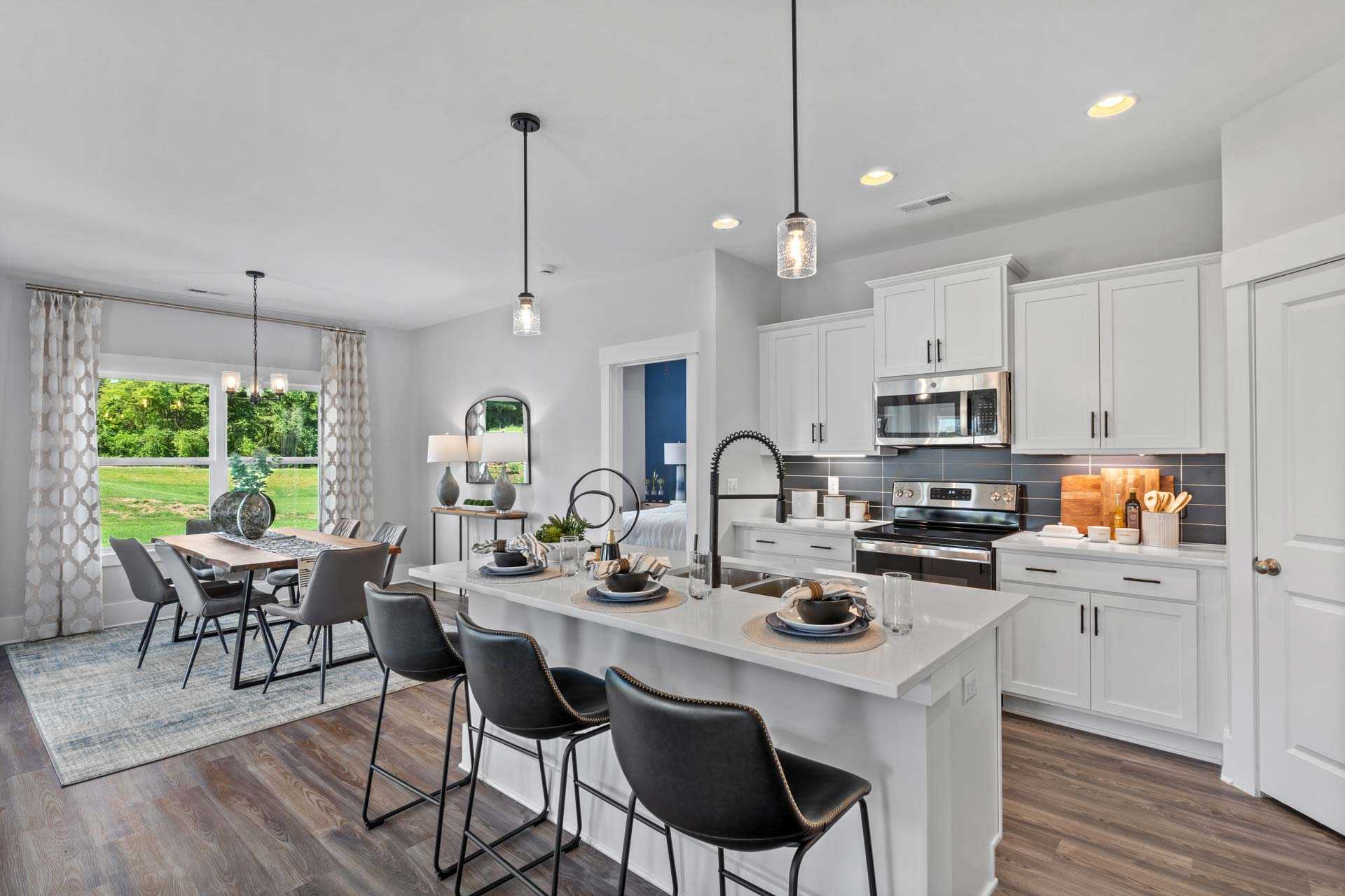 Spacious open-concept kitchen in Blue Spring Huntsville AL with white cabinetry, large island, dining table, hardwood floors