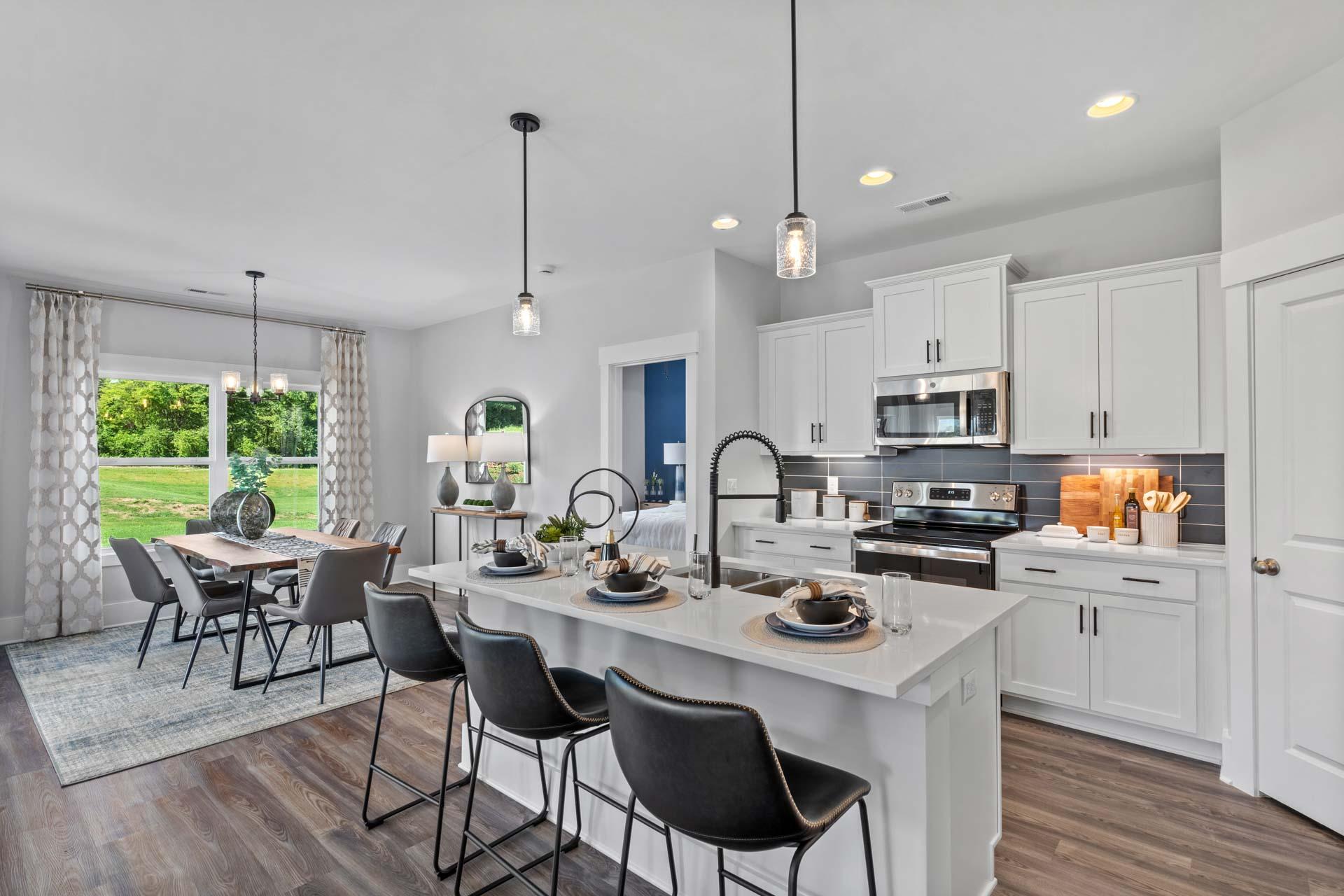 Spacious open-concept kitchen in Blue Spring Huntsville AL with white cabinetry, large island, dining table, hardwood floors