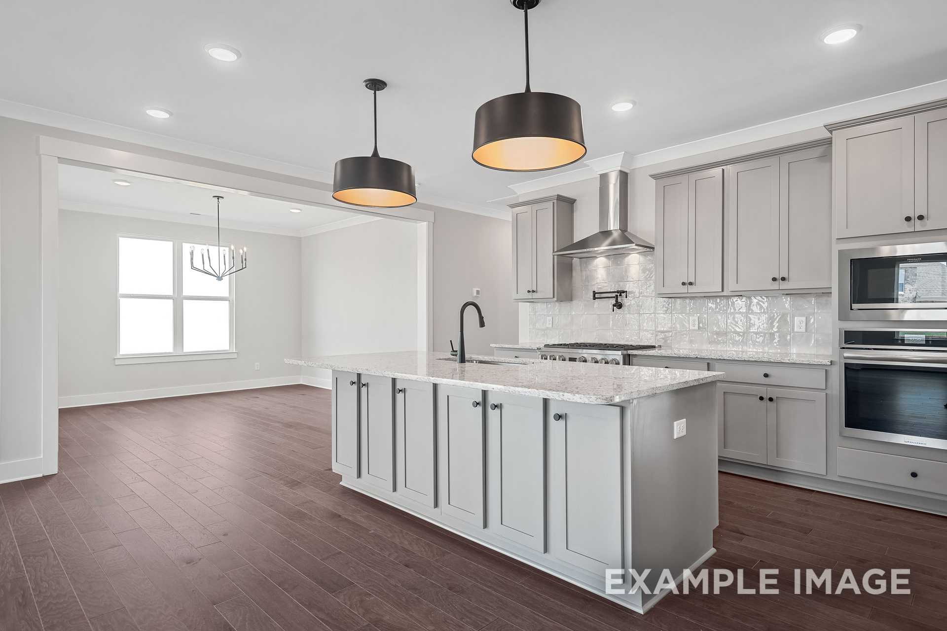 Modern kitchen in The Hathaway with large center island, light gray shaker cabinets, stainless appliances, subway tile backsplash, and open dining area