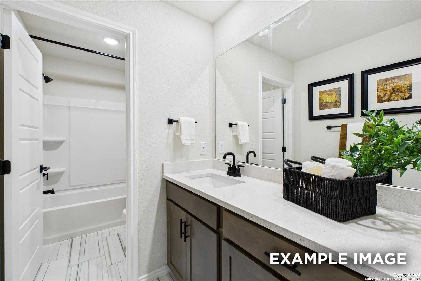 Modern secondary bathroom with white quartz vanity, deep tub, frameless mirror in Davidson Homes Florence C, San Antonio