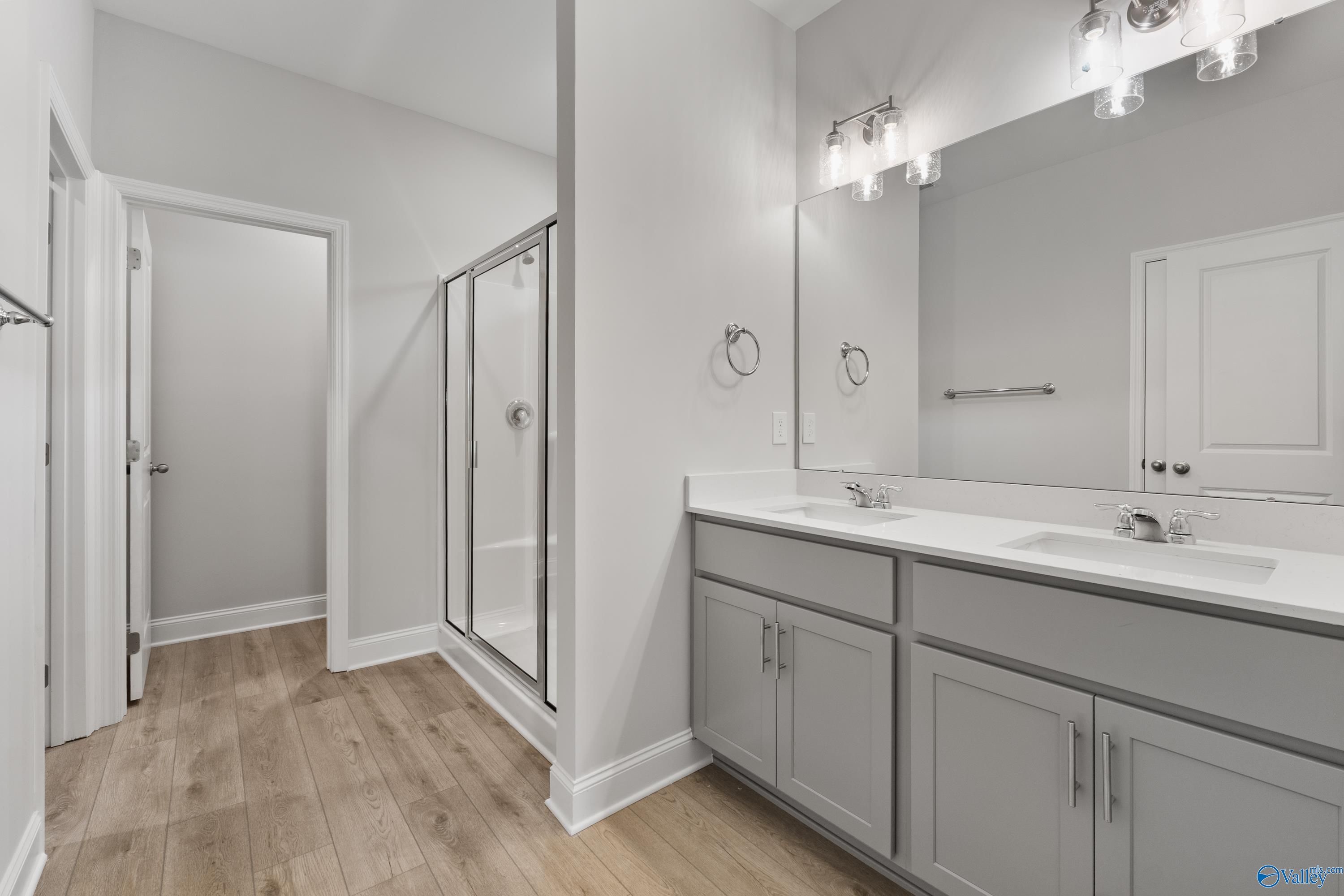 Modern master bathroom featuring double vanity, glass shower, and gray cabinets in Davidson Homes The Daphne C, Huntsville, AL